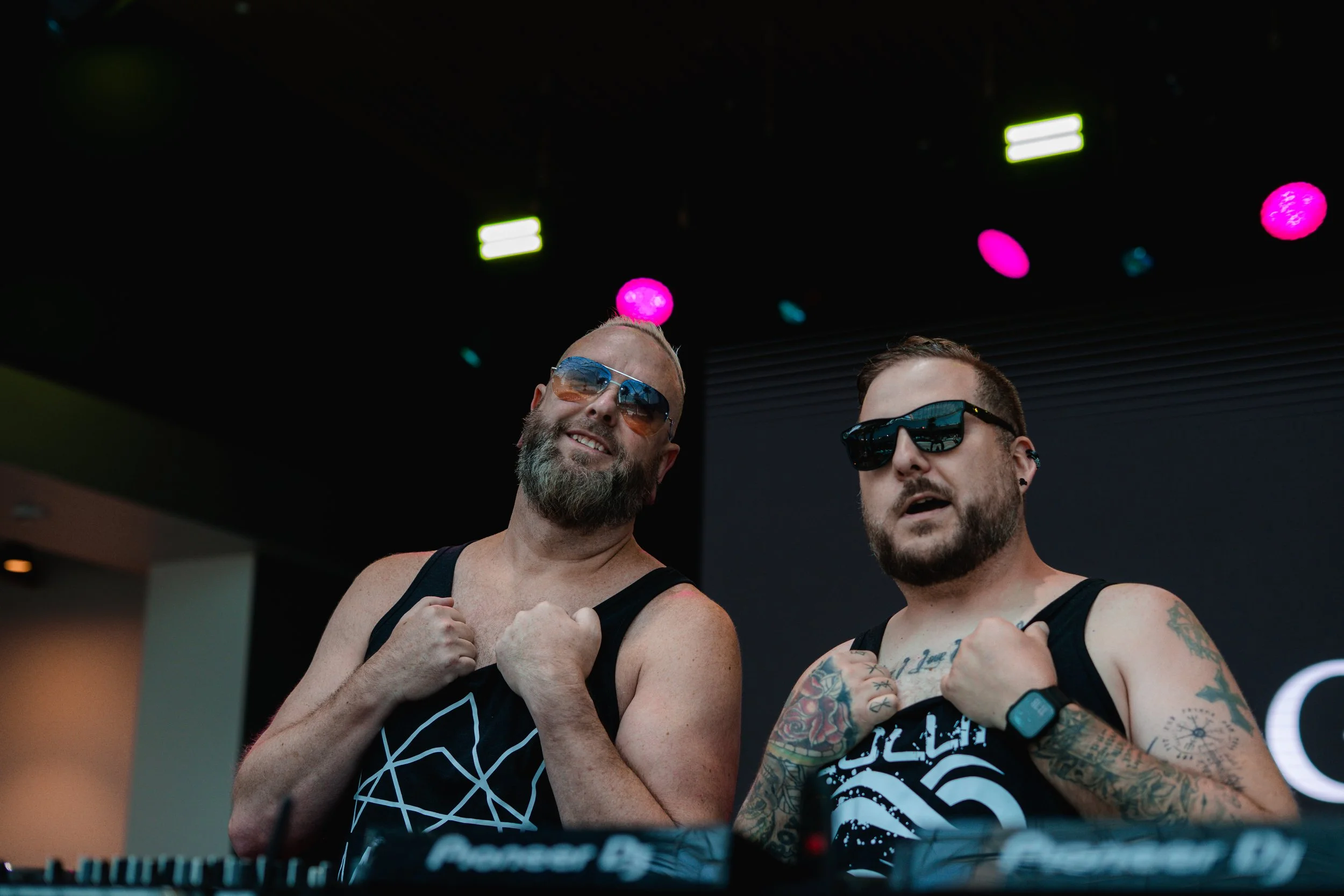 A DJ with tattoos, mattb and collin chaos console in a dark club environment. artist prominent dj grand rapids ready for bookings and big festivals, artist, founder remedy collective djs sound production morris media byron morris