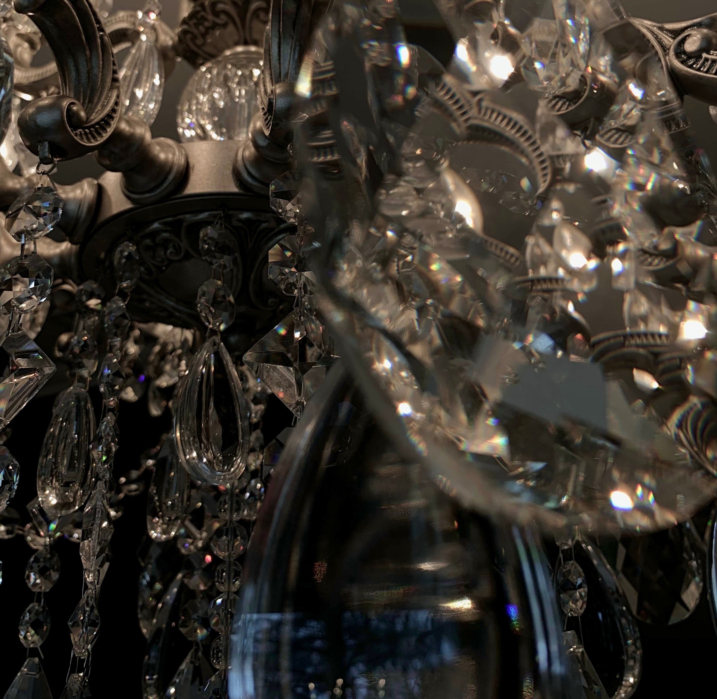 Close-up of a decorative chandelier with hanging crystal prisms and ornate black metal base.