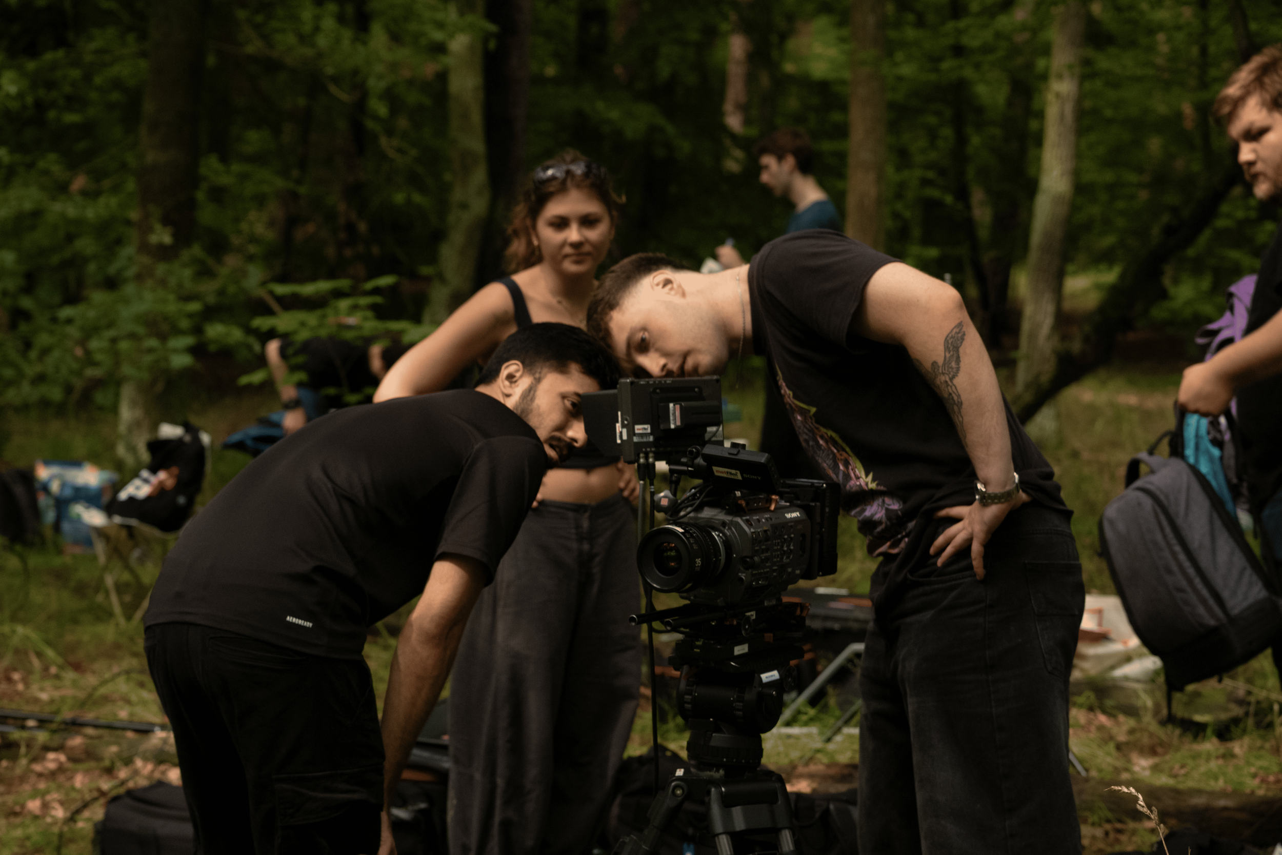 Group of people filming with a professional camera in a wooded outdoor setting.