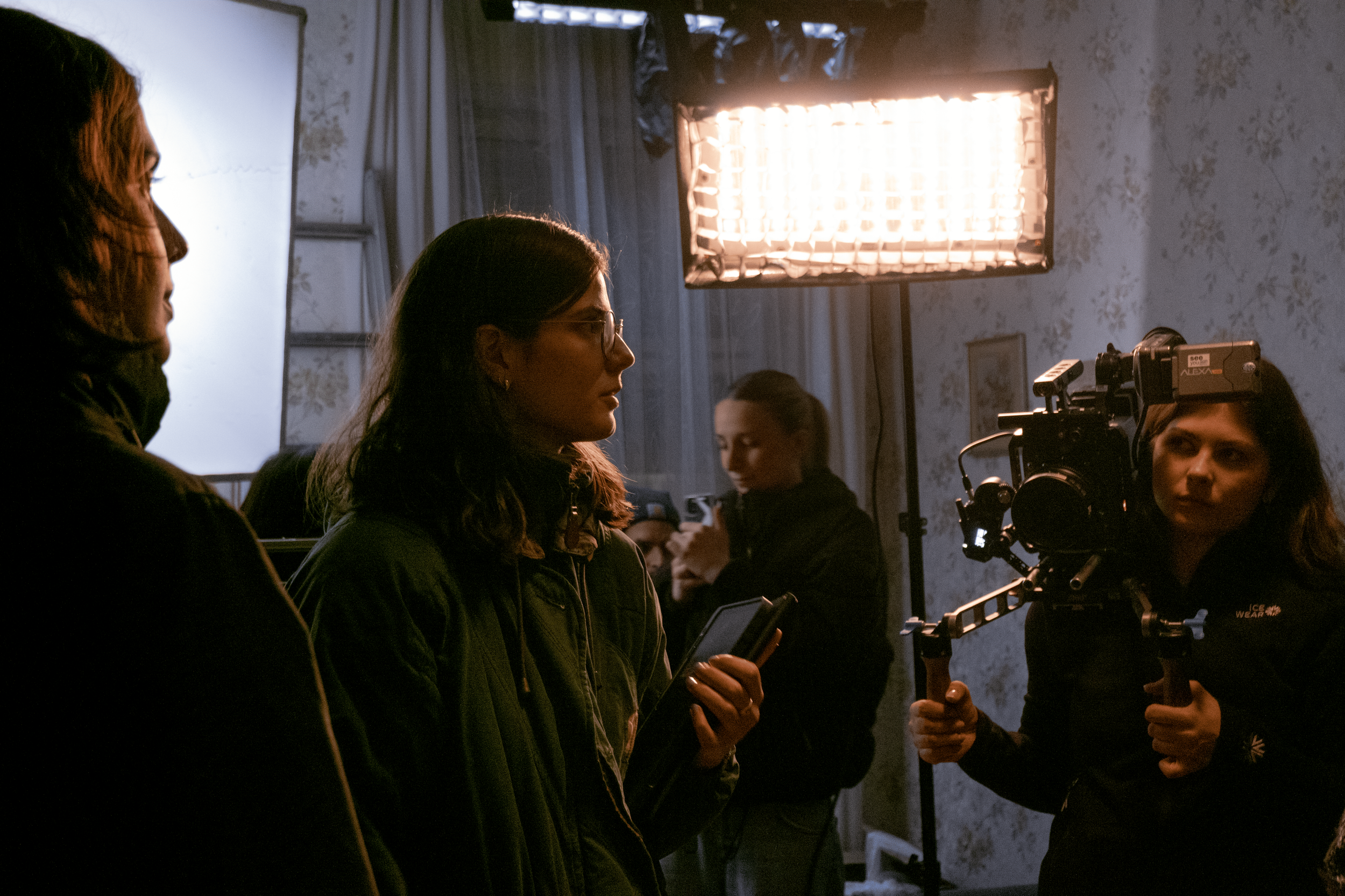 Filmmakers and crew working on a film set with professional lighting and camera equipment in an indoor setting.