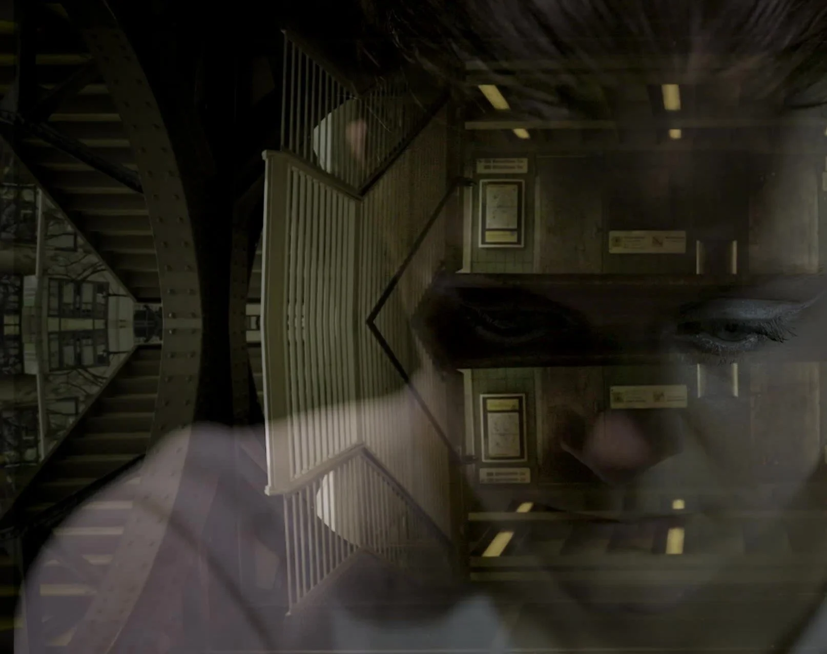 A reflection of a person's face and eyes superimposed over an interior view of a staircase and hallway in a building.