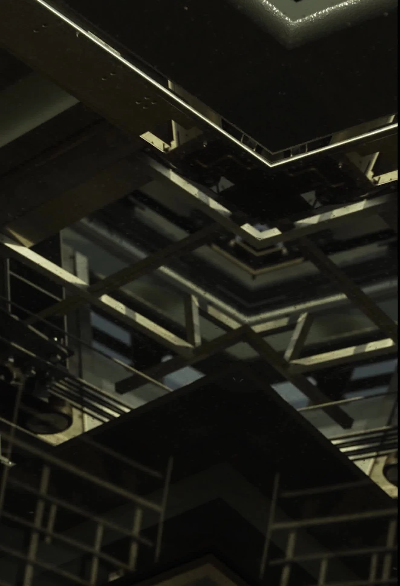 A dark, industrial indoor space with metallic frameworks and structures, potentially part of a building under construction or maintenance.