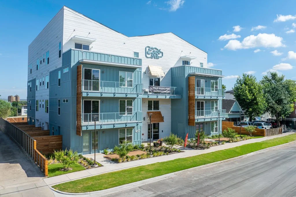 Modern multi-story apartment building with balconies and landscaped front yard