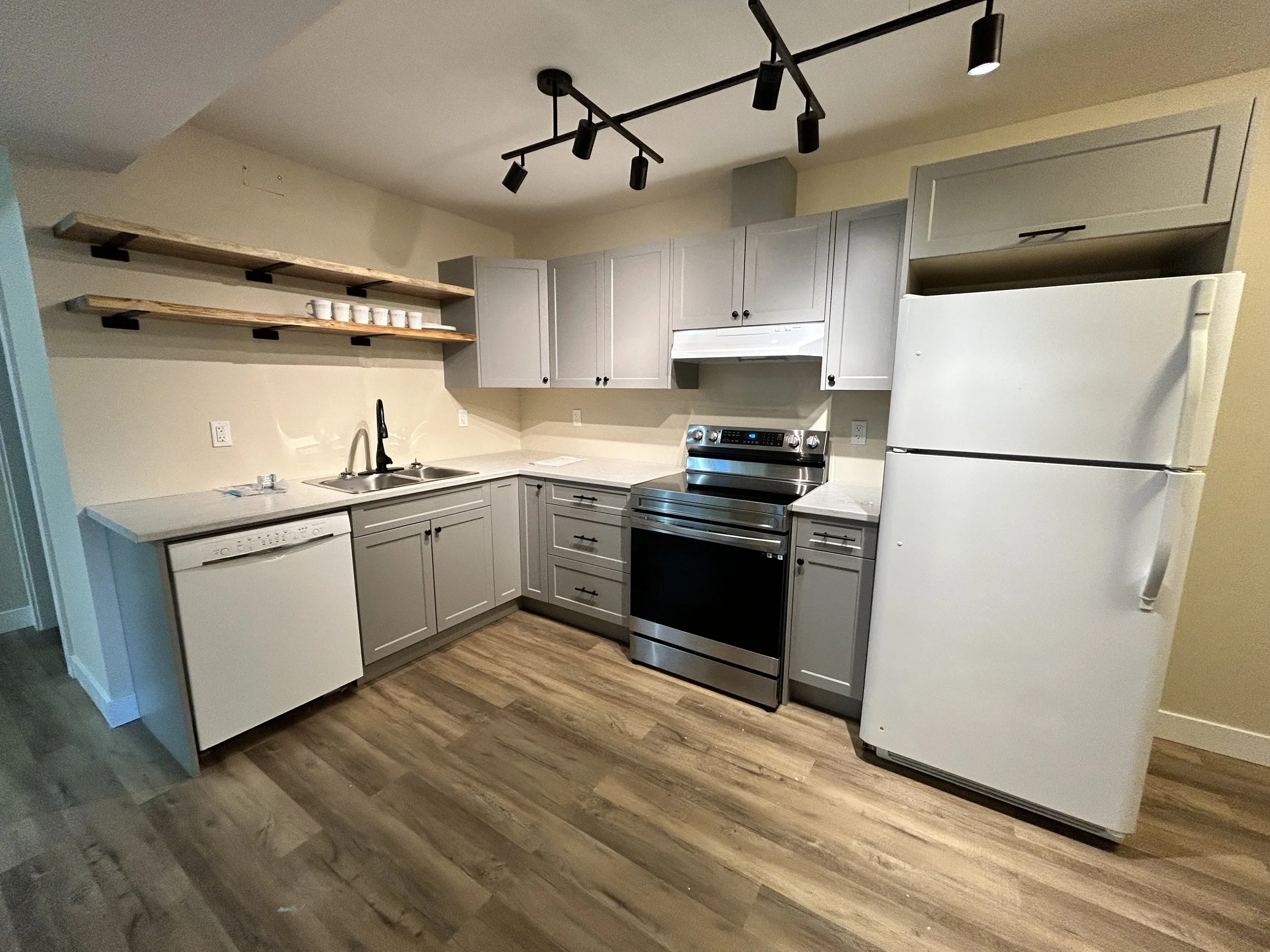 New kitchen in basement suite. Grey cabinets. New kitchen cabinets made by contractor for a new secondary suite. New basement suite with floating live-edge shelves, new flooring, new drywall. Smithers contractor.