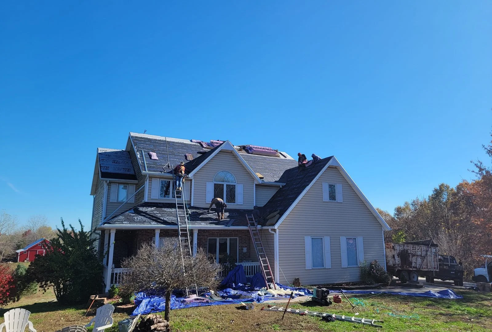 Roofing crew installing new shingles on a two-story home