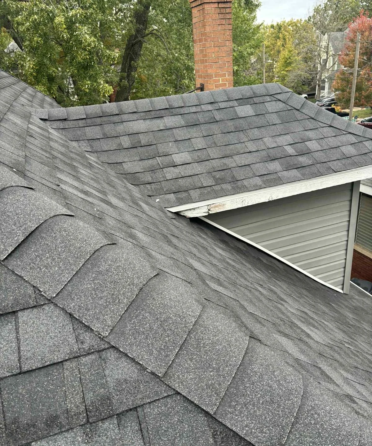 Gray architectural shingles installed around a chimney and dormer