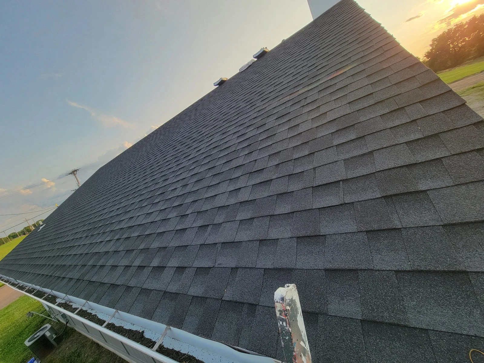 Completed dark asphalt shingle roof in evening light
