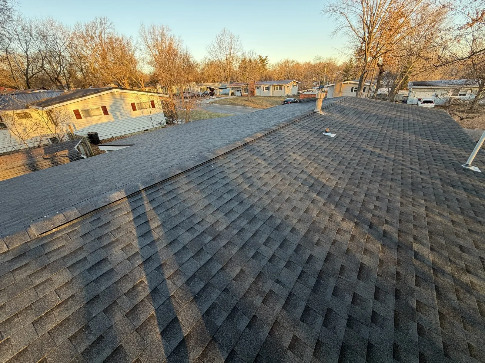 Completed dark architectural shingle roof at golden hour