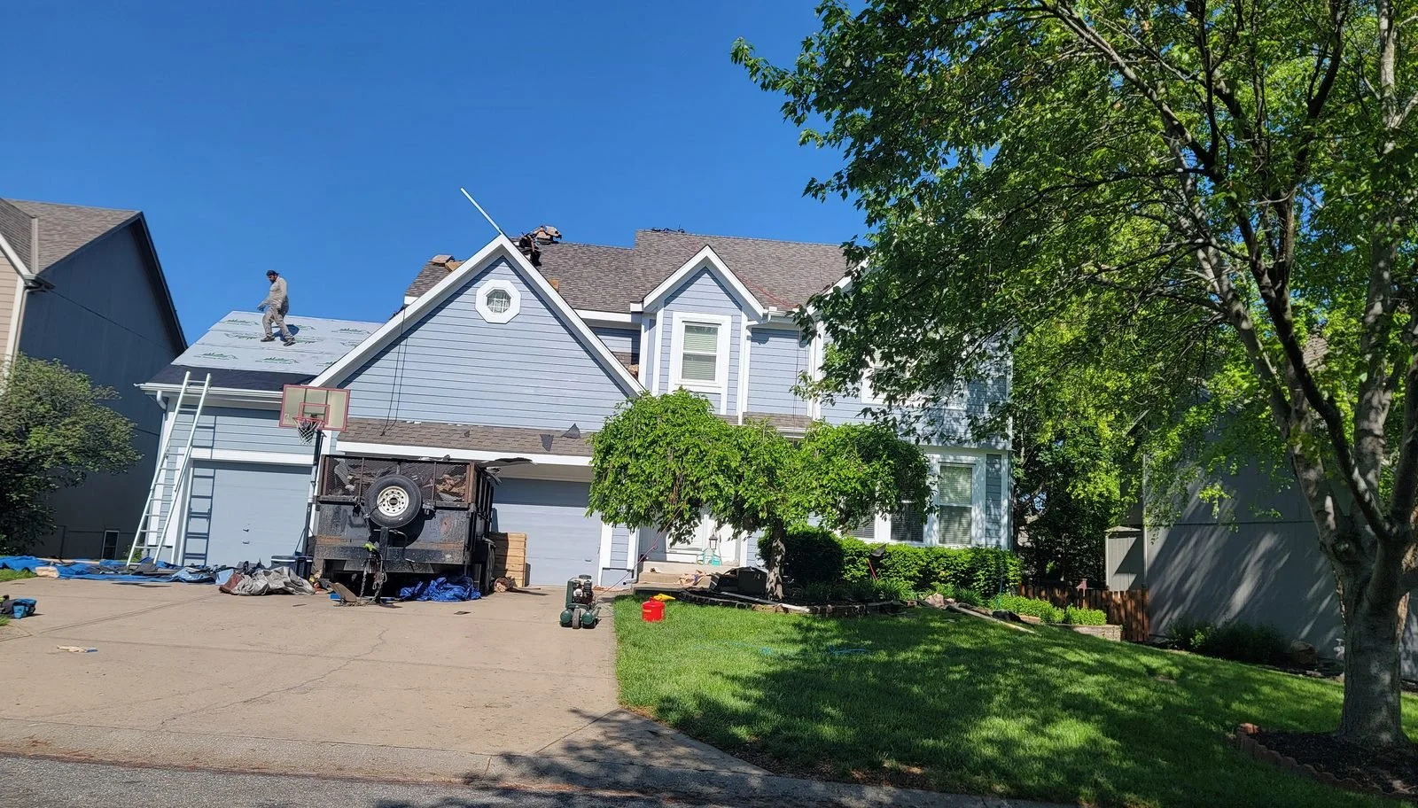 Roofer on the roof of a two-story home during a roof replacement