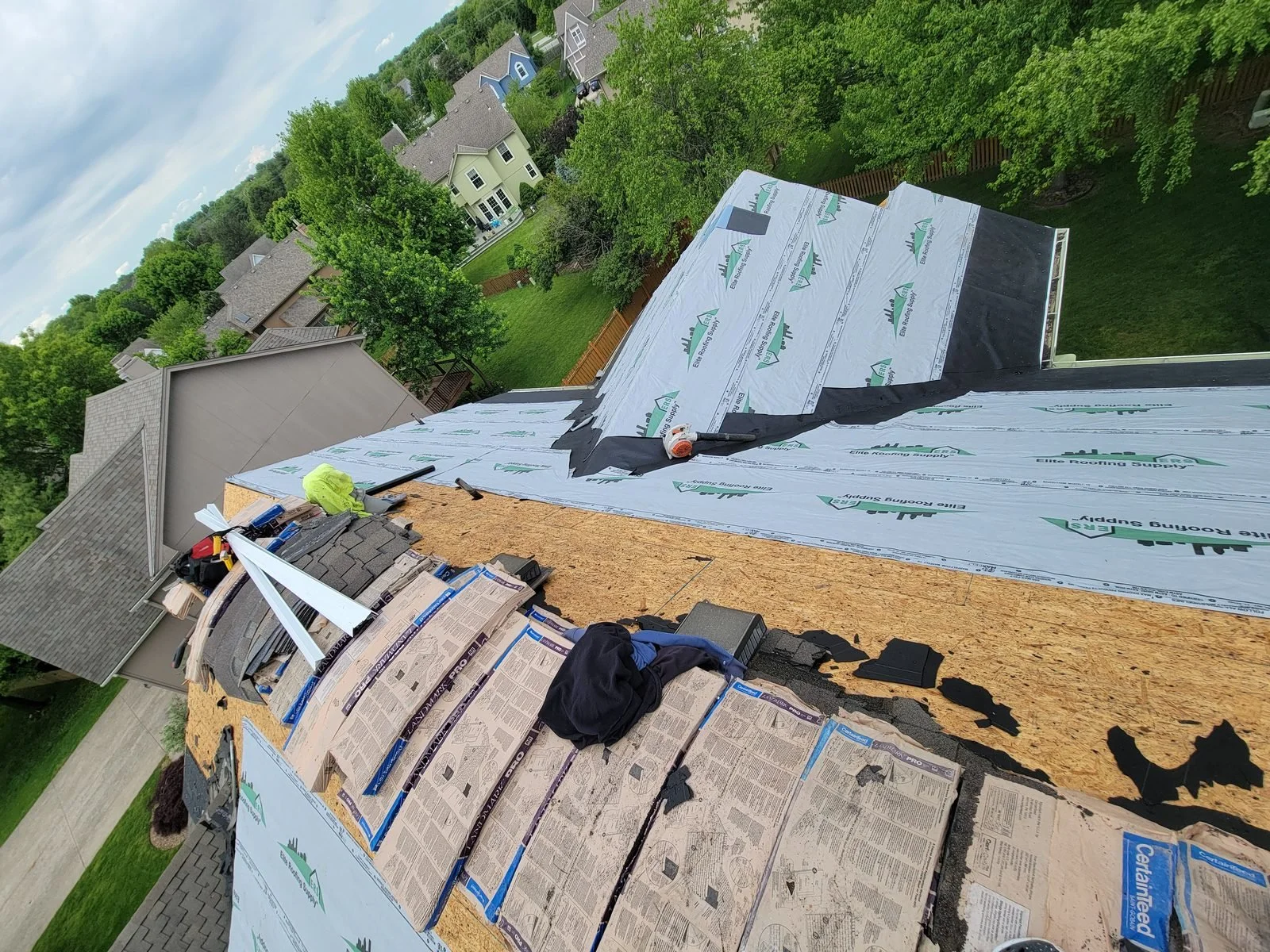 Old shingles removed during a roof tear-off, with underlayment being installed