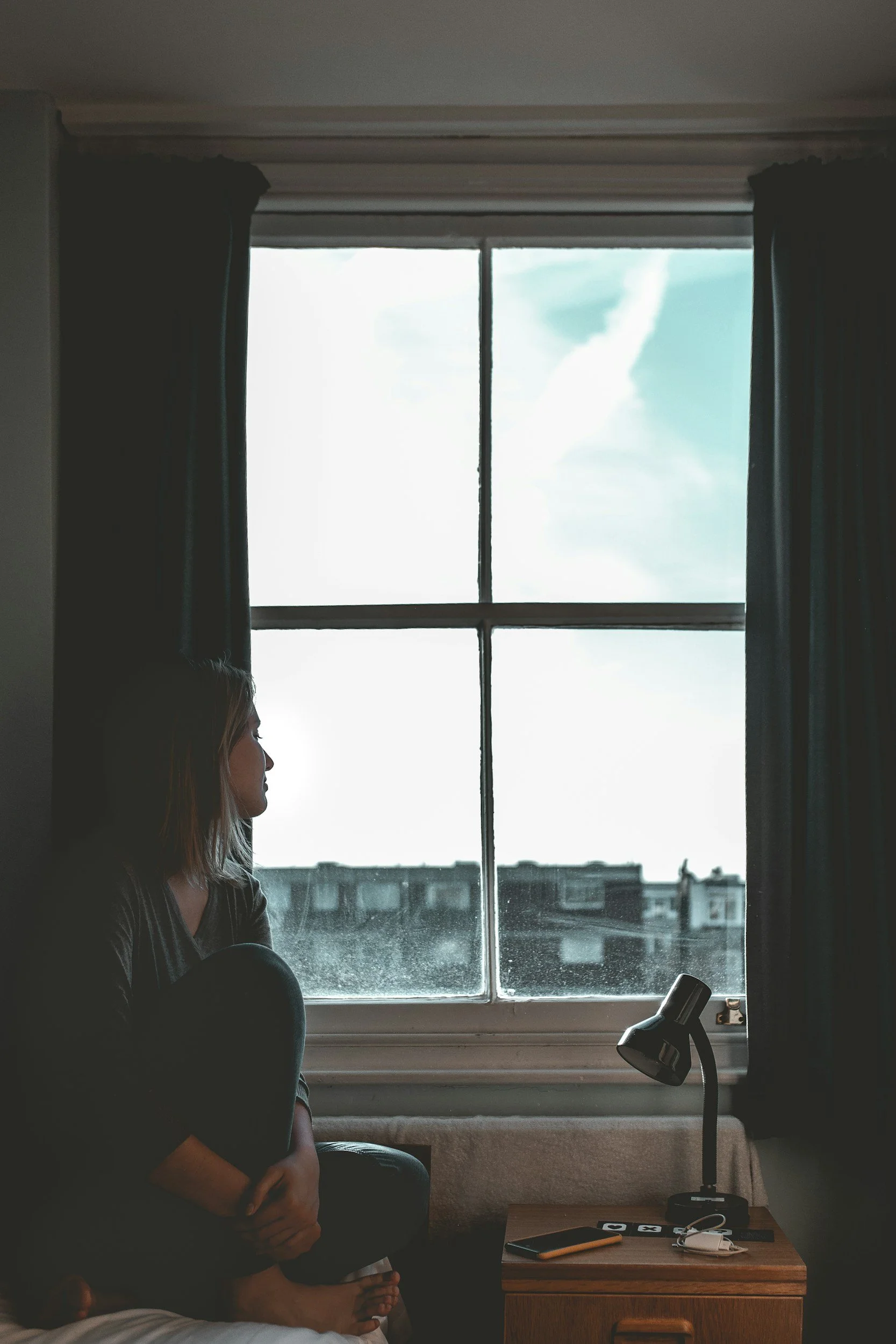 Person sitting by window reflecting during high-functioning burnout in Philadelphia.