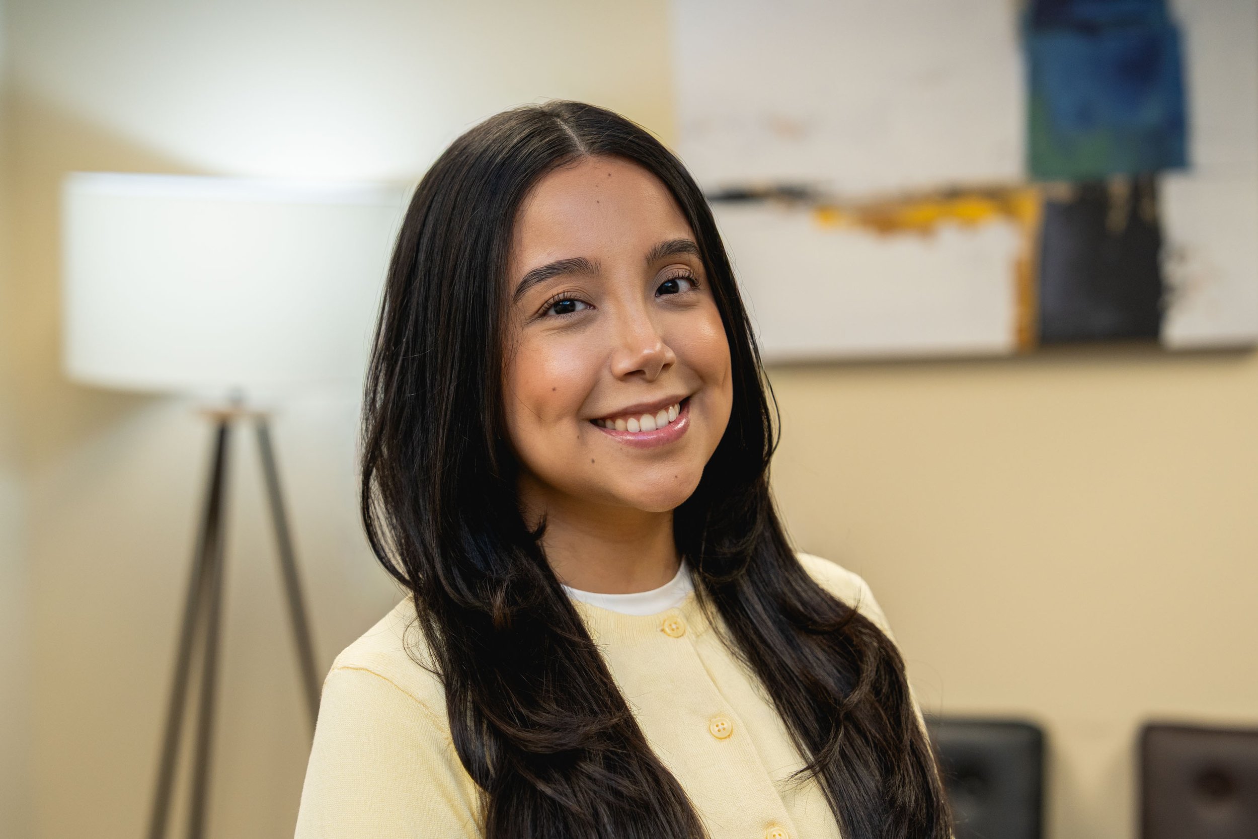 A woman stands in front of a clock.
