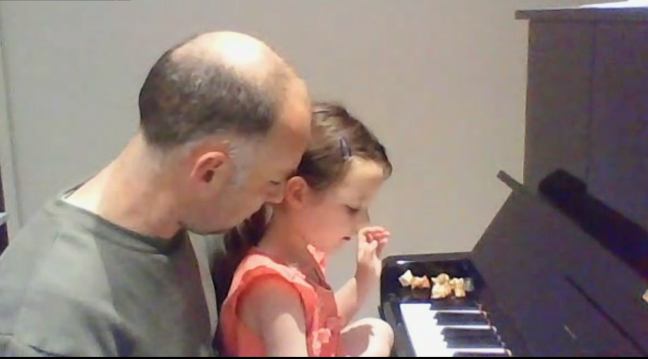 Child sitting with parent at piano during lesson