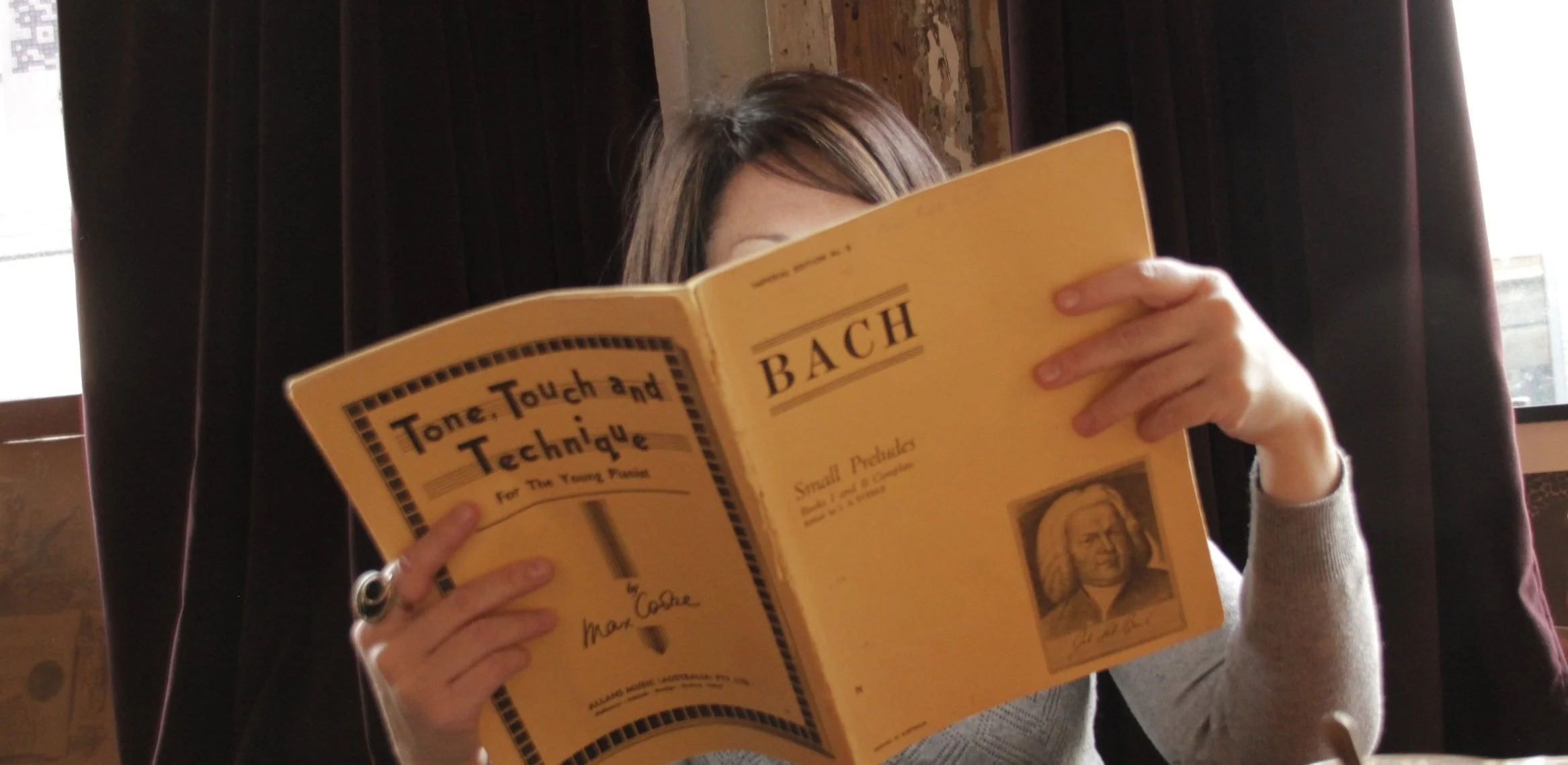 Teacher sitting behind piano book, partially visible from front