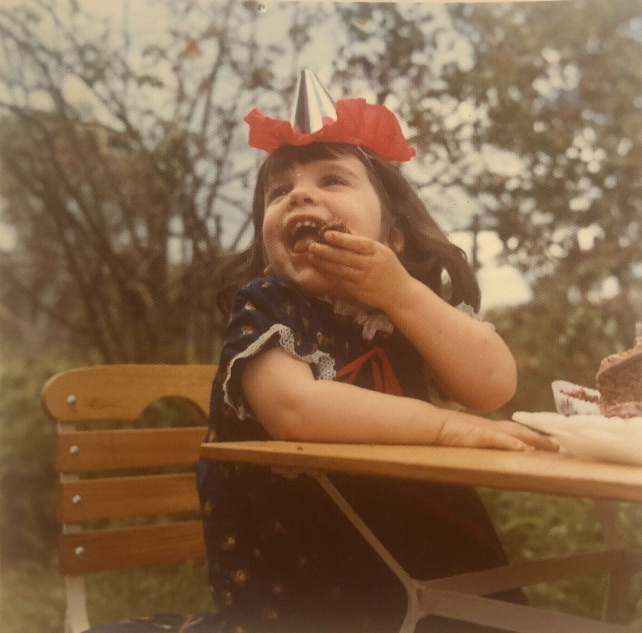 Young child eating chocolate cake, looking up and laughing