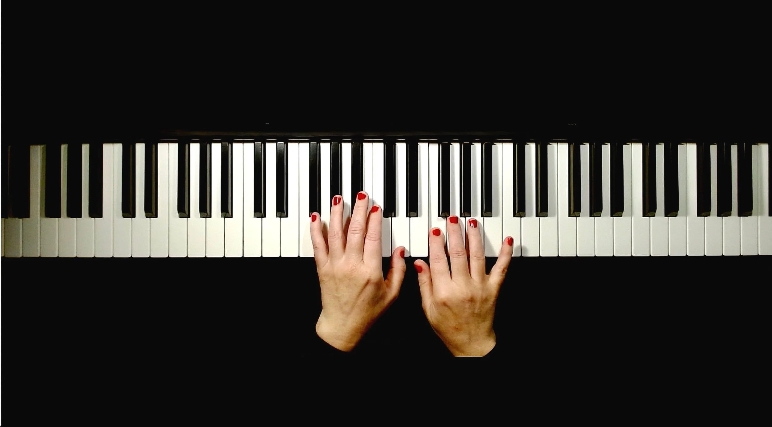 Hands on piano keyboard during online lesson, top view