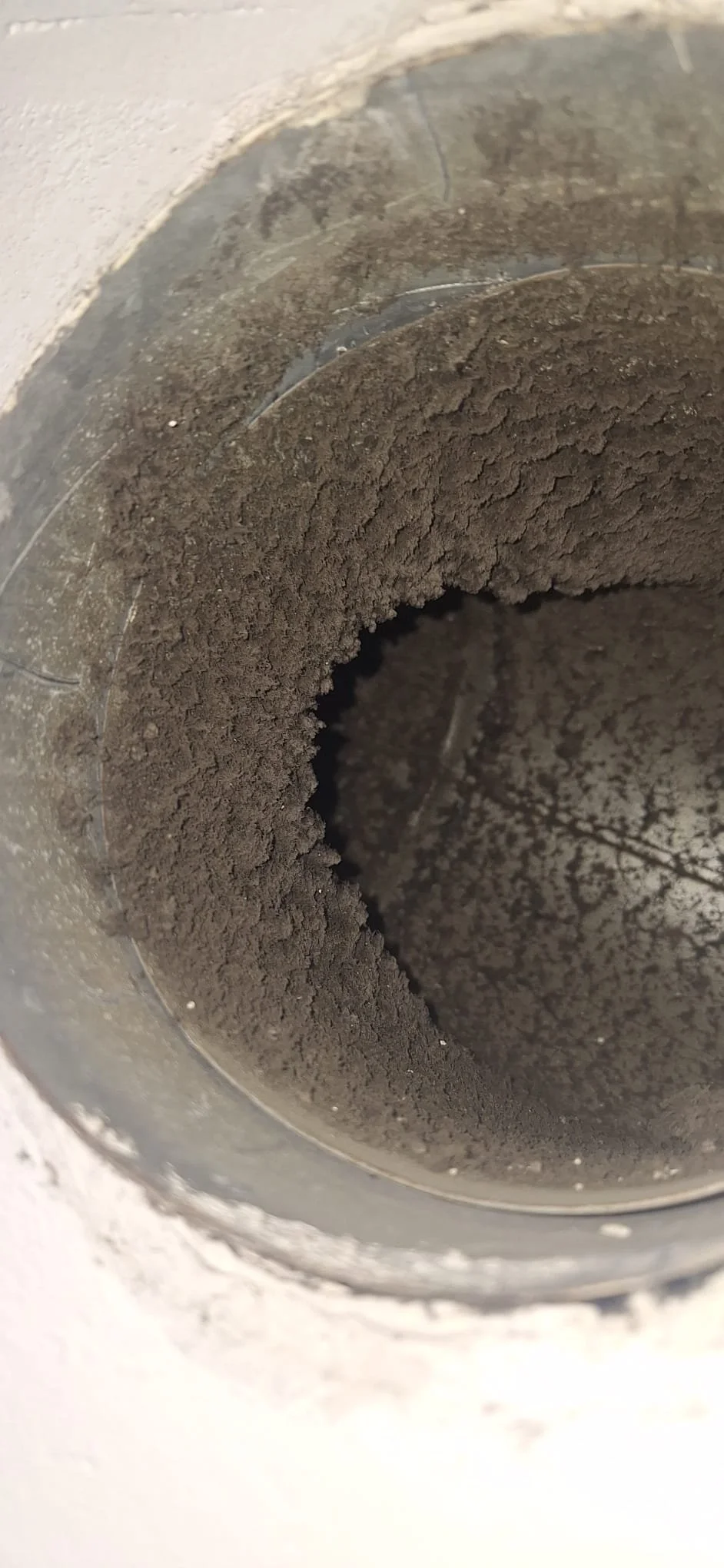 Close-up of a pipe filled with dark brown soil.