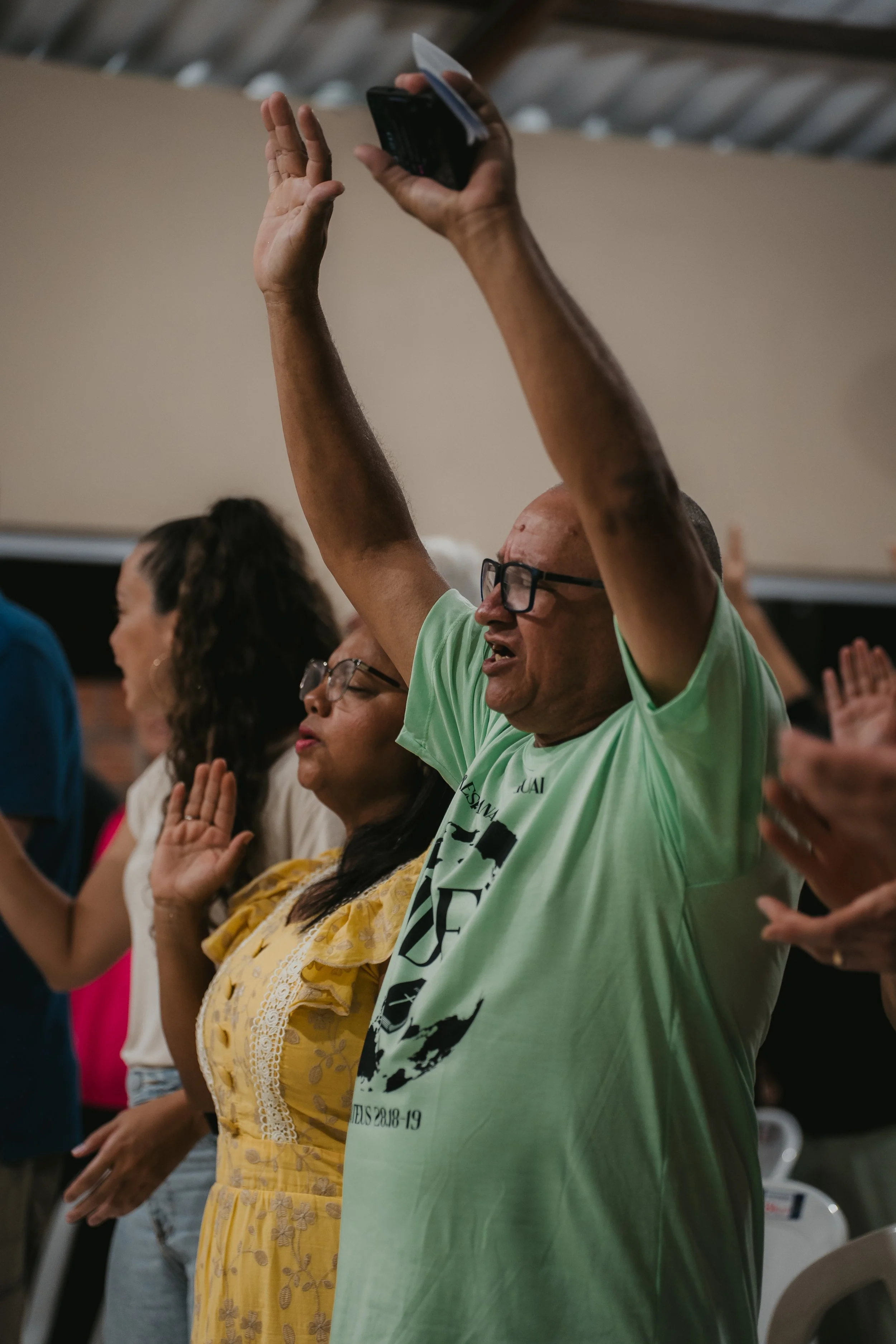 People raising hands in prayer or worship during a church service or gathering.
