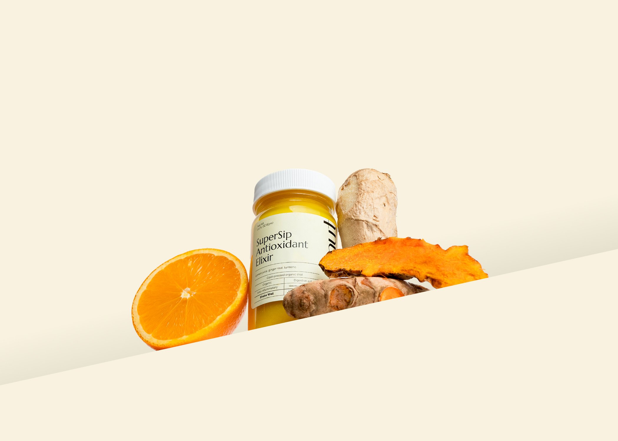 SuperSip Antioxidant Elixir with turmeric, ginger root, and an orange slice against a light background.
