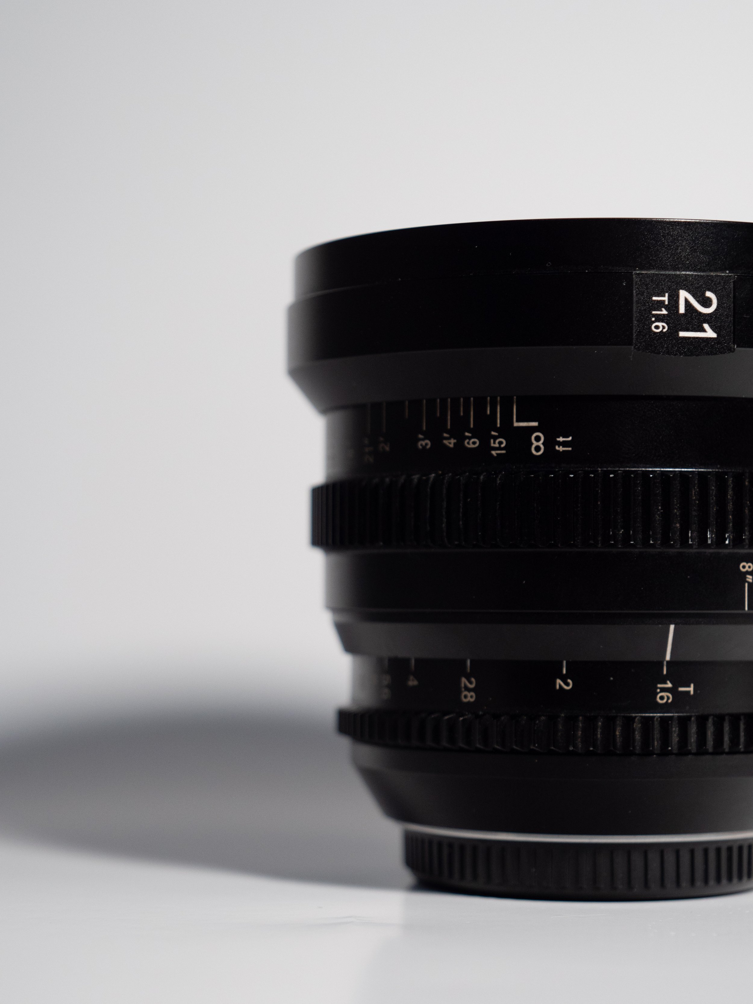 Black camera lens with aperture and focus markings, labeled 21mm T1.6.