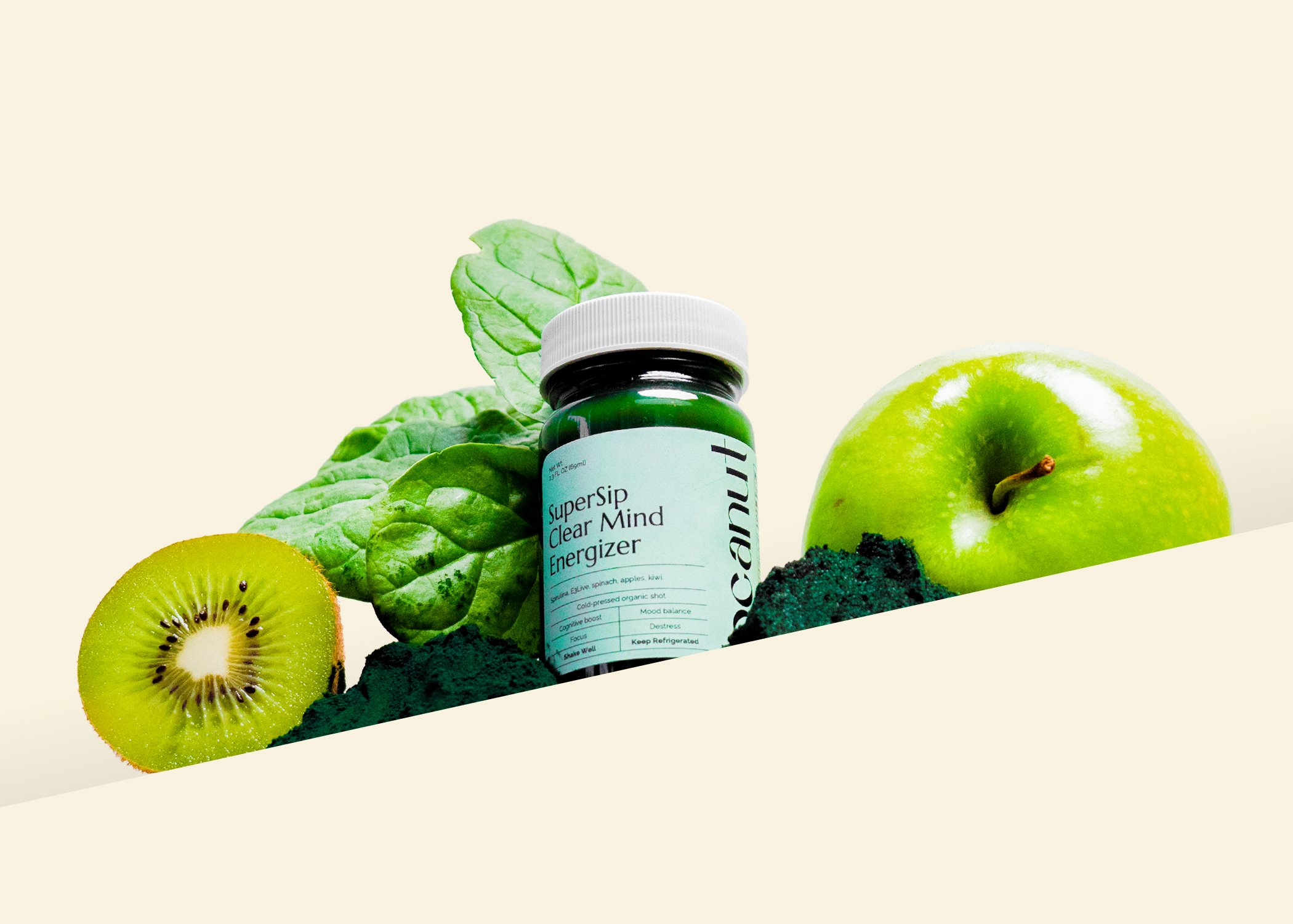 Green juice bottle labeled 'SuperSip Clear Mind Energizer' surrounded by fresh spinach leaves, a sliced kiwi, a green apple, and spirulina powder.