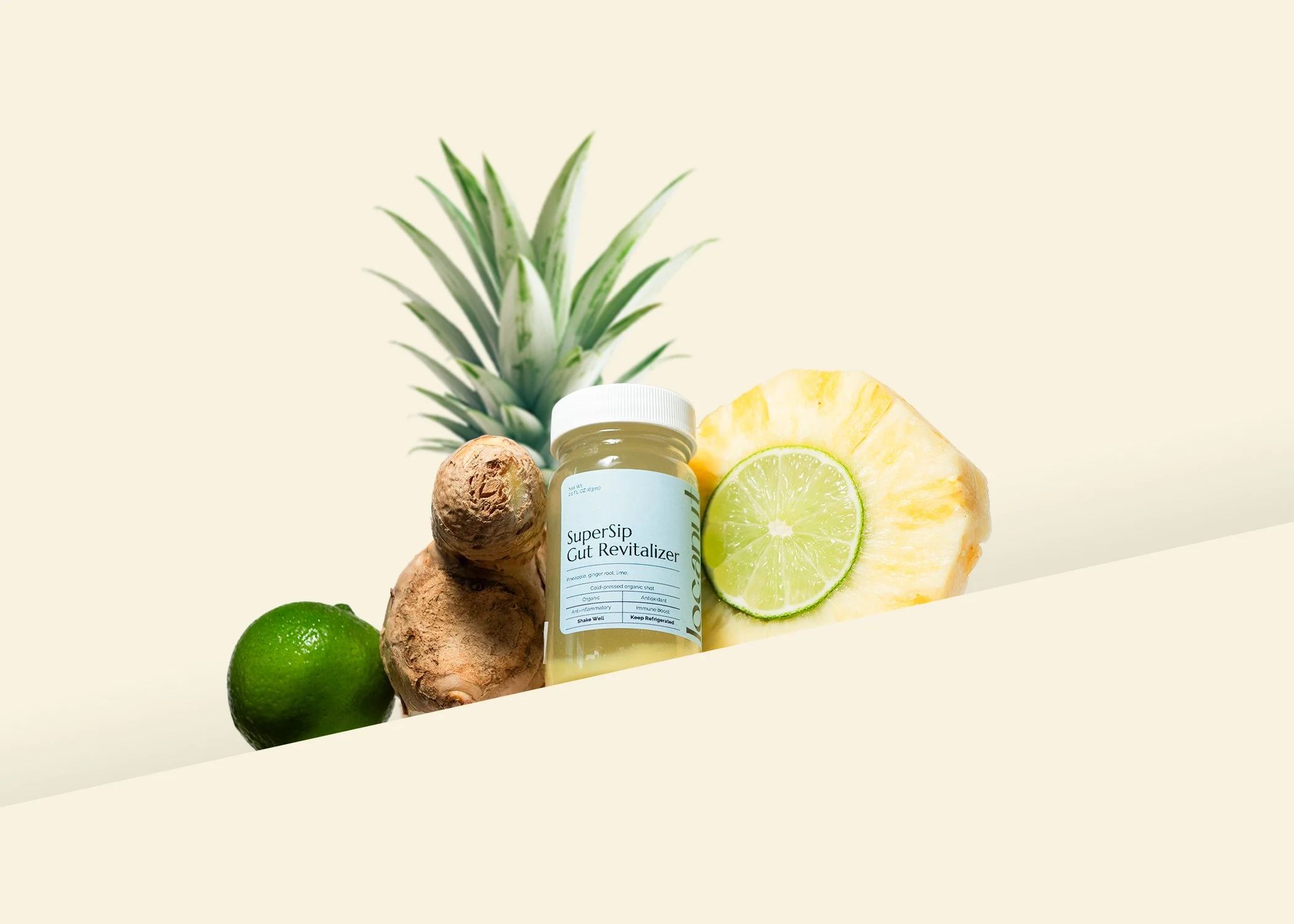 Jar of Supersip Gut Revitalizer surrounded by pineapple, lime, and ginger on a light background.