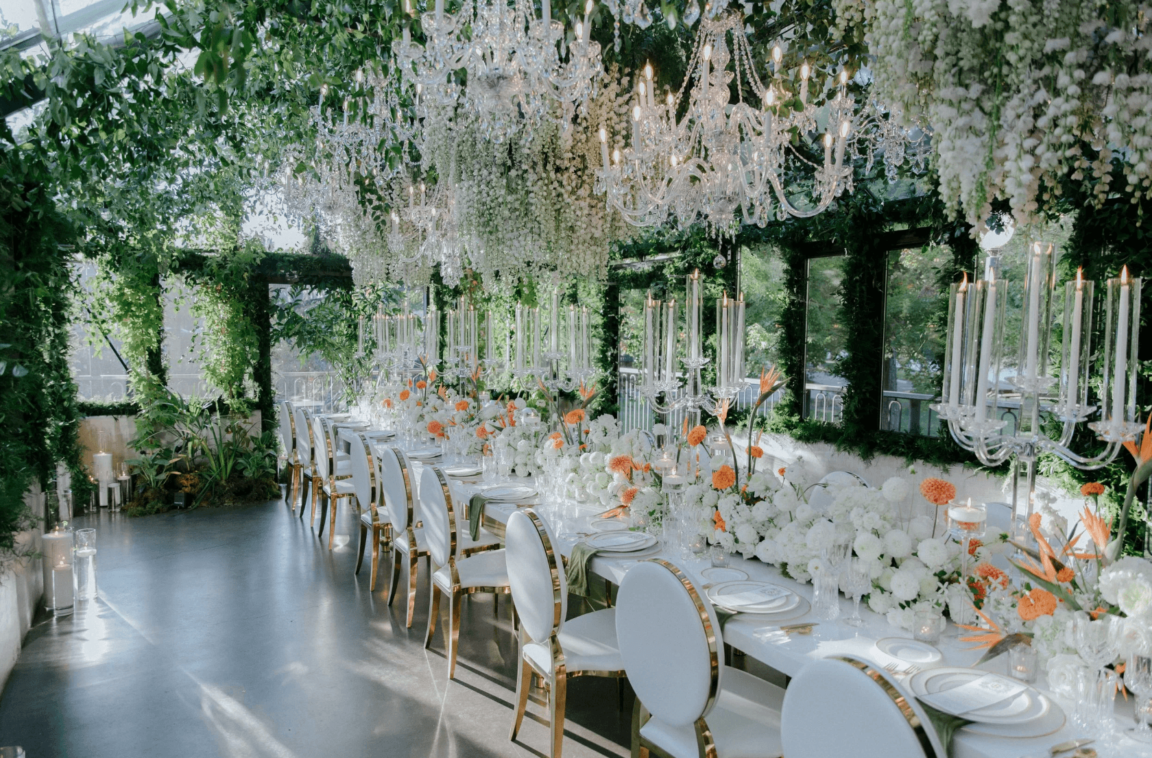 Luxury wedding reception with lush greenery, floral installations, and crystal chandeliers over an elegant dining table