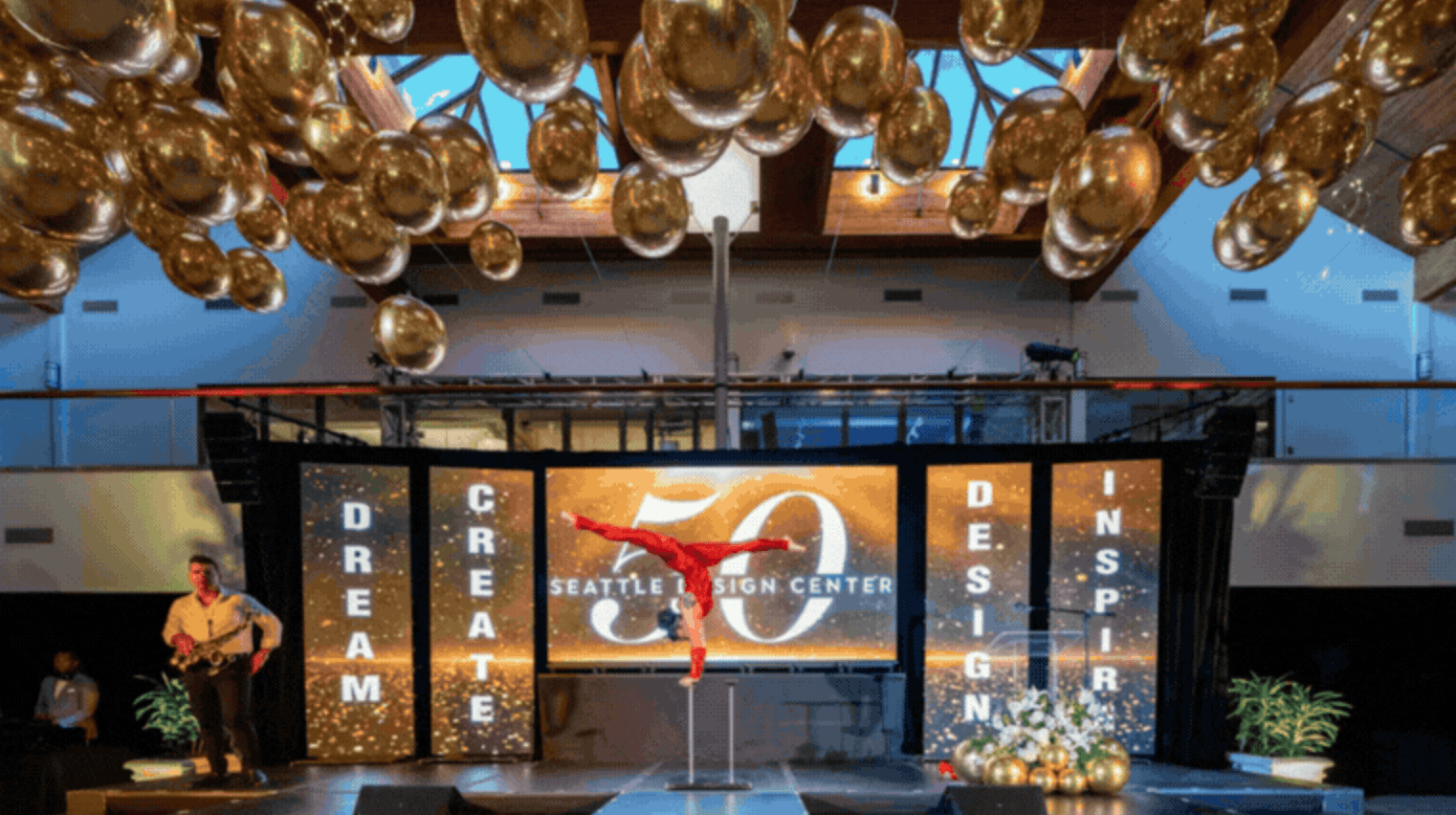 Aerial performer on stage at a Gian Events brand activation at Seattle Design Center with gold balloon installation and event production lighting