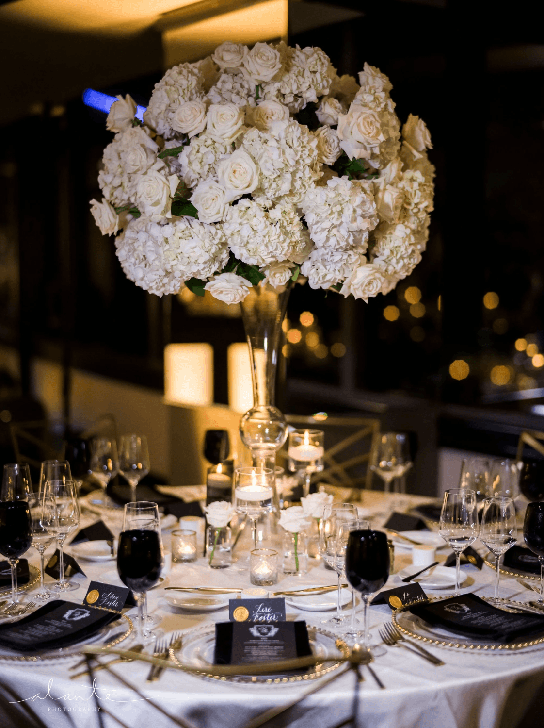 Luxury wedding reception table with tall white floral centerpiece, candlelight accents, and elegant place settings designed by Gian Events