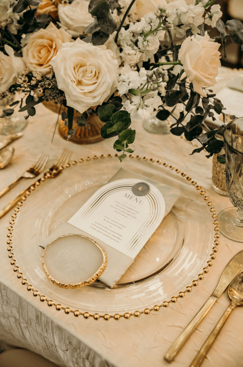 Luxury wedding place setting with gold flatware, menu card, and floral centerpiece detail designed by Gian Events