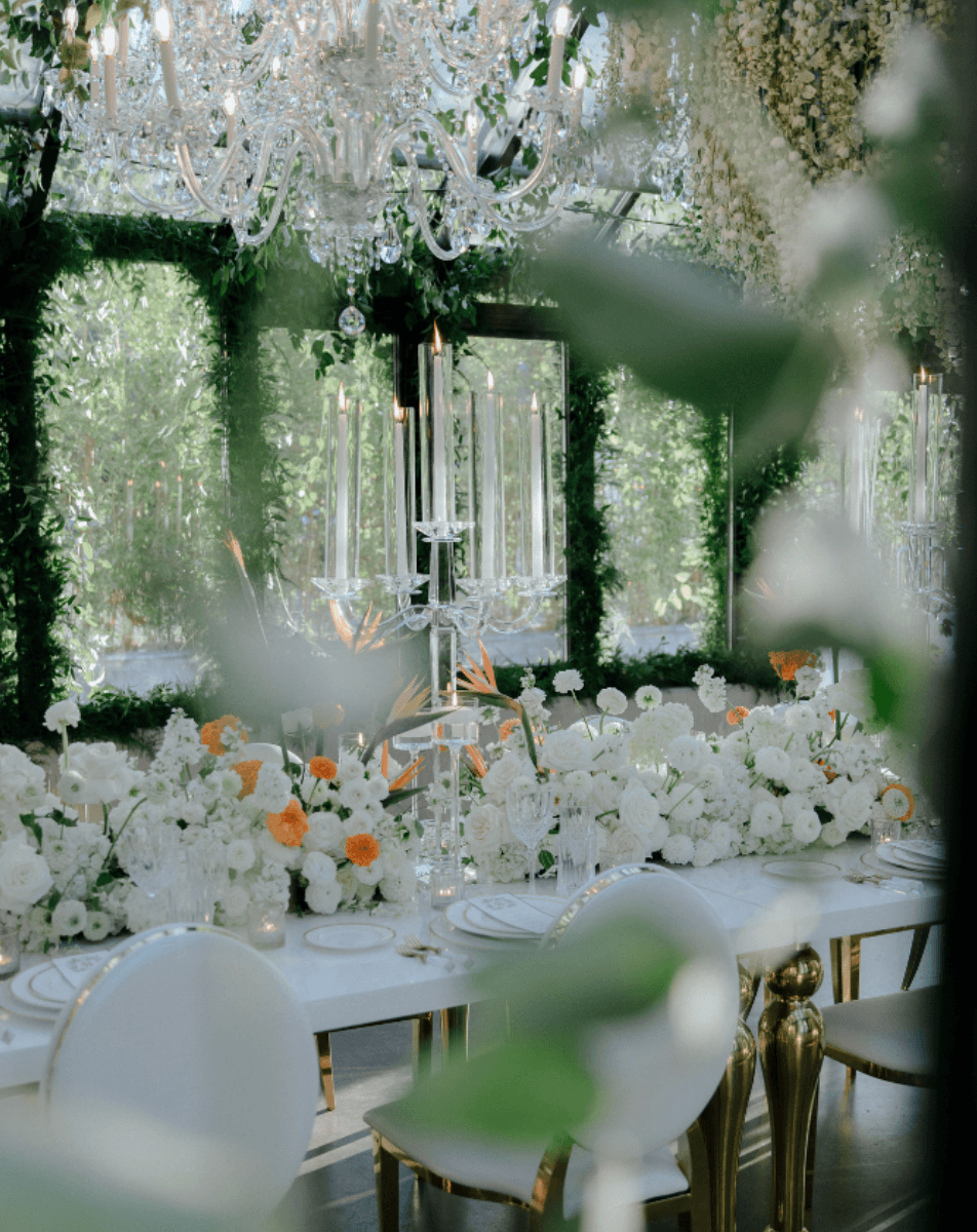 Luxury wedding reception table with chandelier lighting and floral design in an elegant glasshouse setting by Gian Events