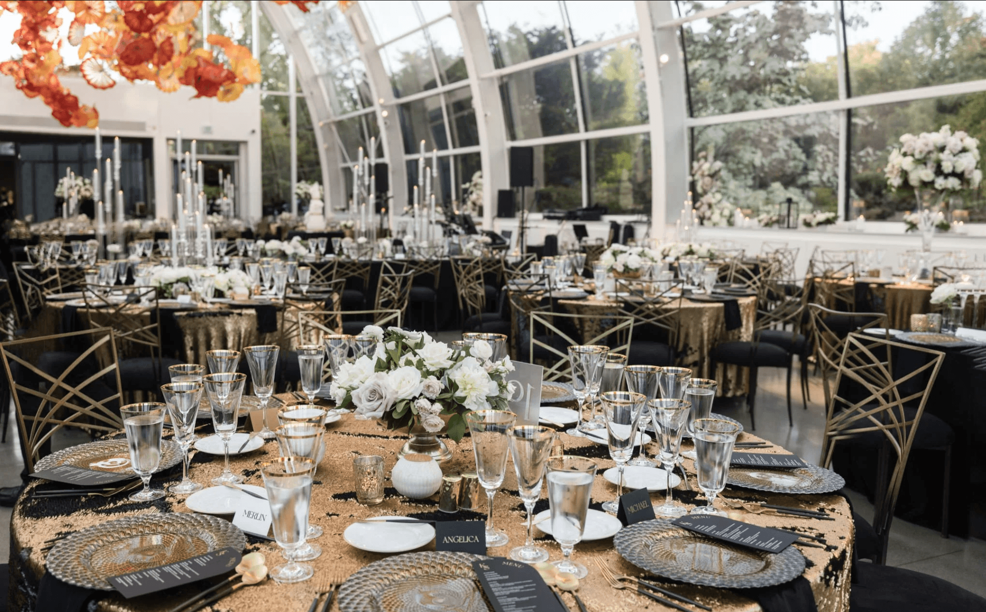 Luxury gala reception table with gold and black design, floral centerpieces, and elegant place settings at a glasshouse venue by Gian Events