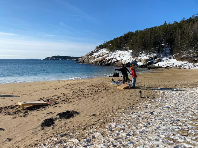 students playing corn hole on a beach