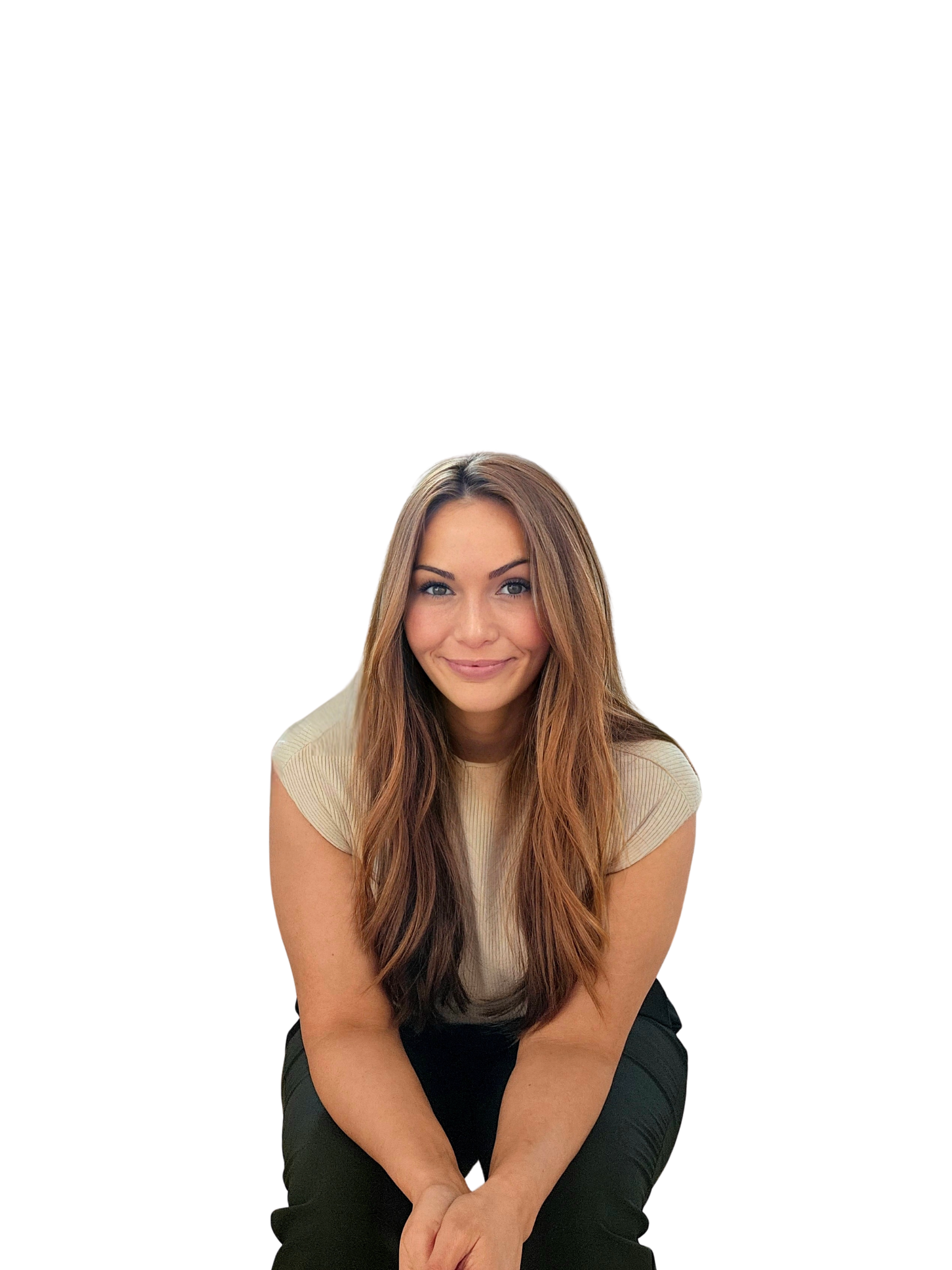 A young woman with long brown hair, wearing a beige shirt, sitting and smiling at the camera.