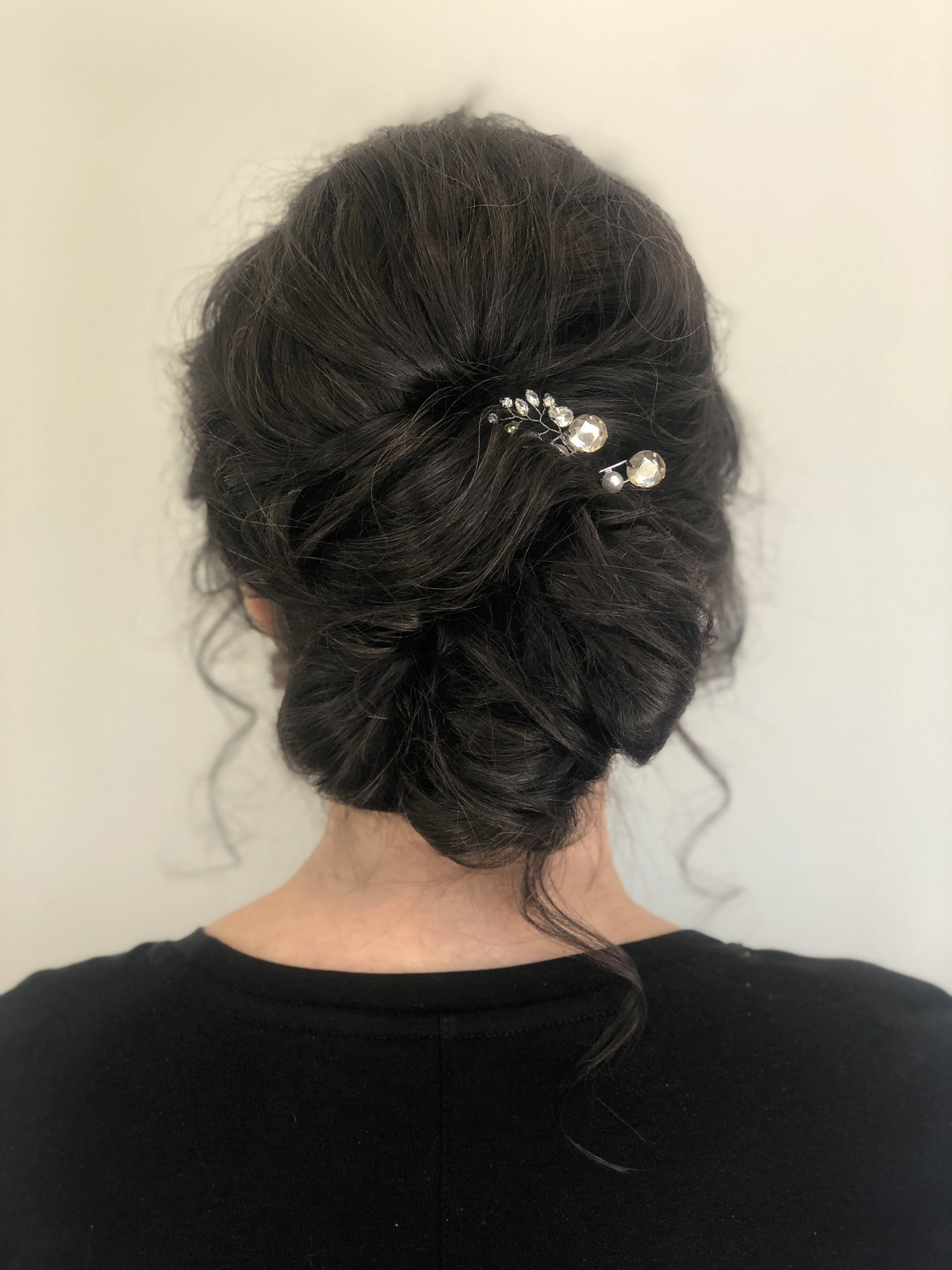 Romantic low bun for curly hair adorned with pearl hair accessory by Maryland bridal stylist
