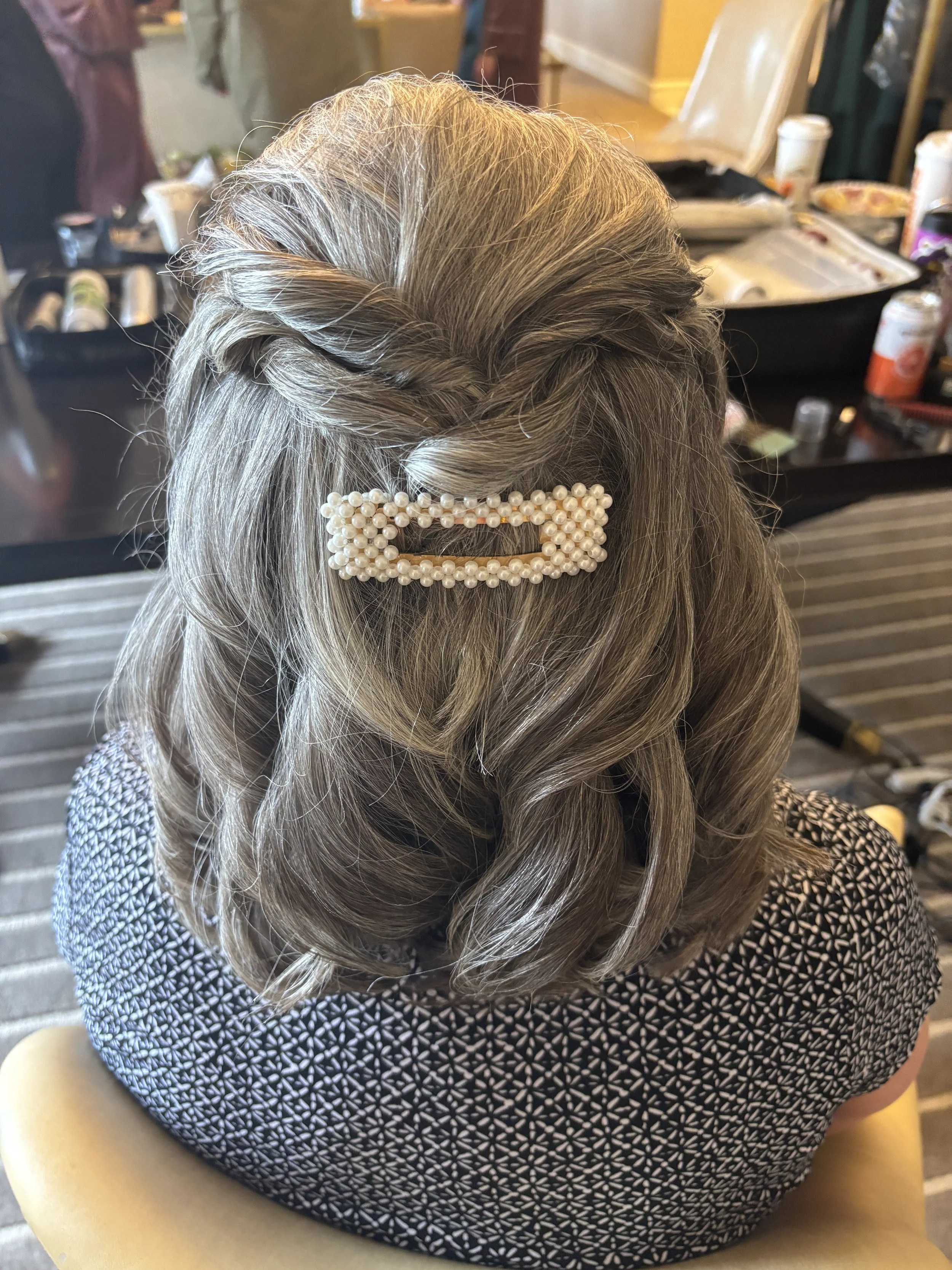 Half up half down wedding hair with twists fastened with a pearl clip
