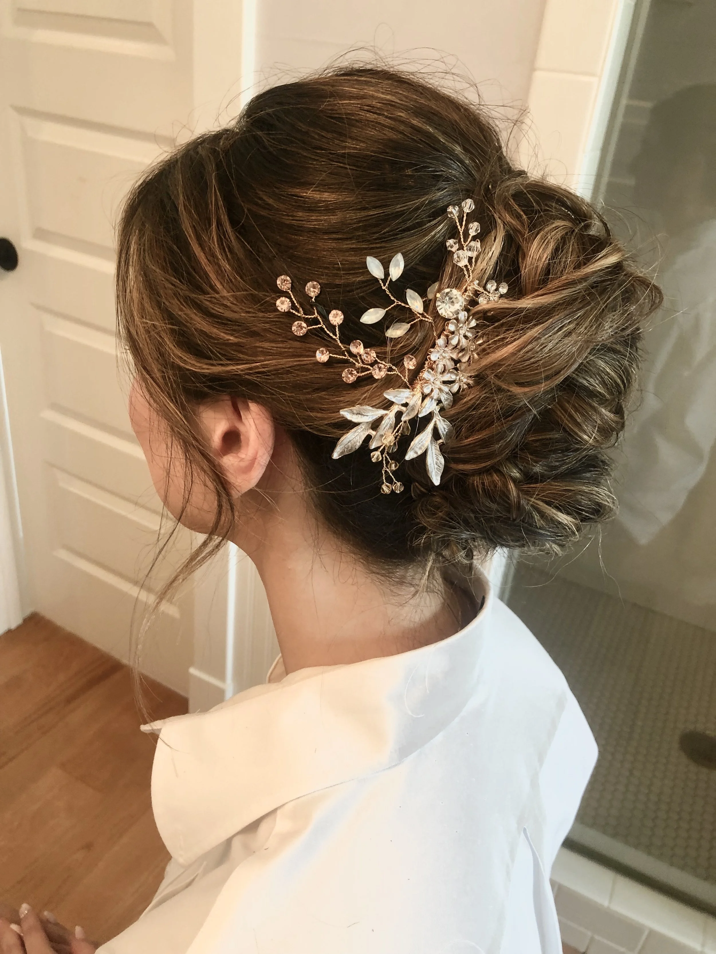wispy and voluminous bridal updo with a natural floral inspired hair accessory