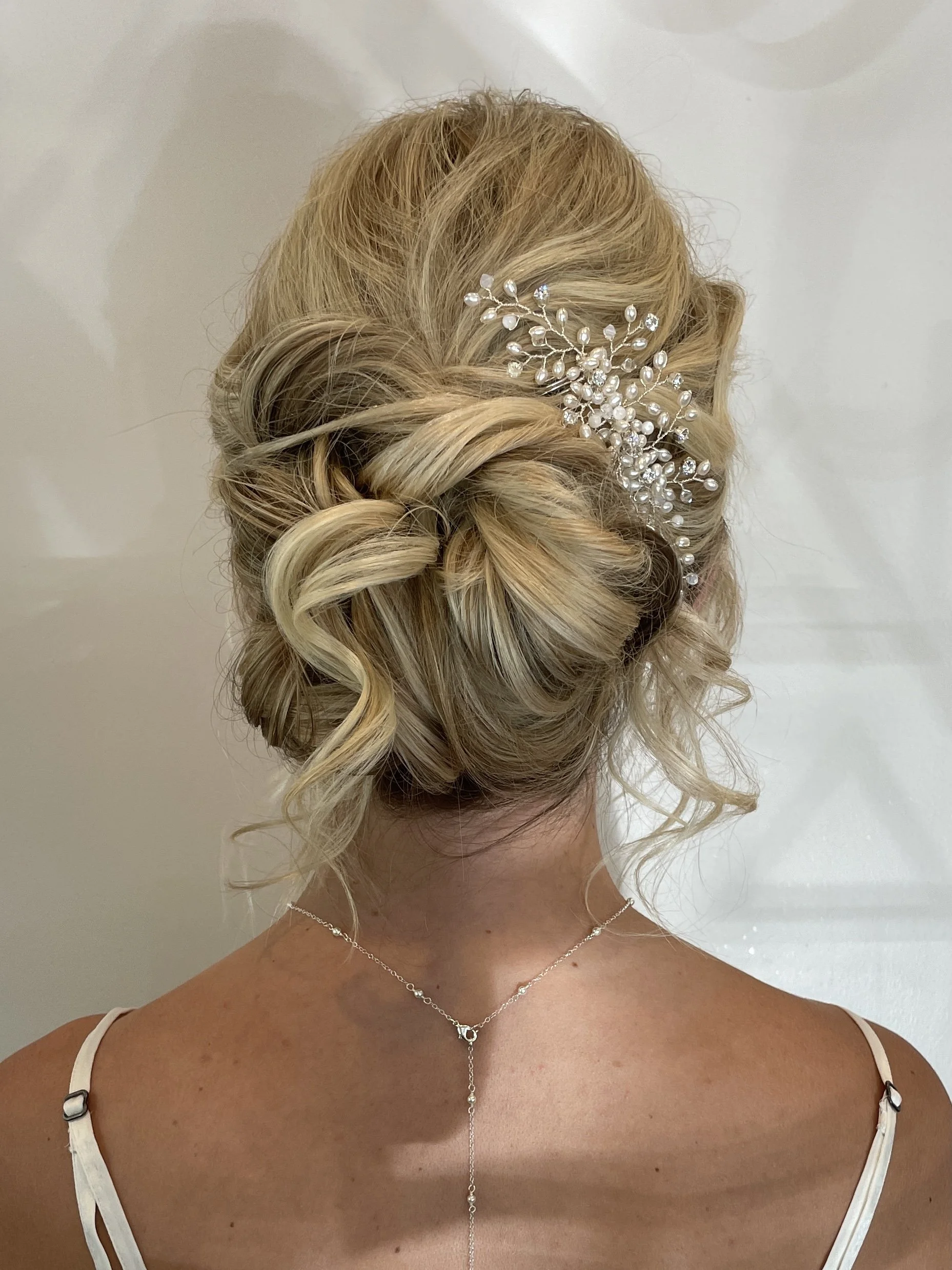 Elegant updo hairstyle adorned with a pearl and crystal hairpiece styled by Frederick, MD beauty artist