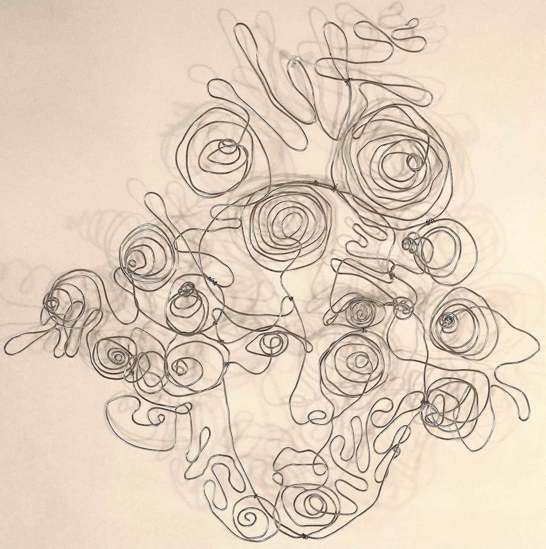 Wire sculpture of interconnected faces created from a single continuous strand, illustrating experimentation with form, movement, and identity for a college art portfolio.