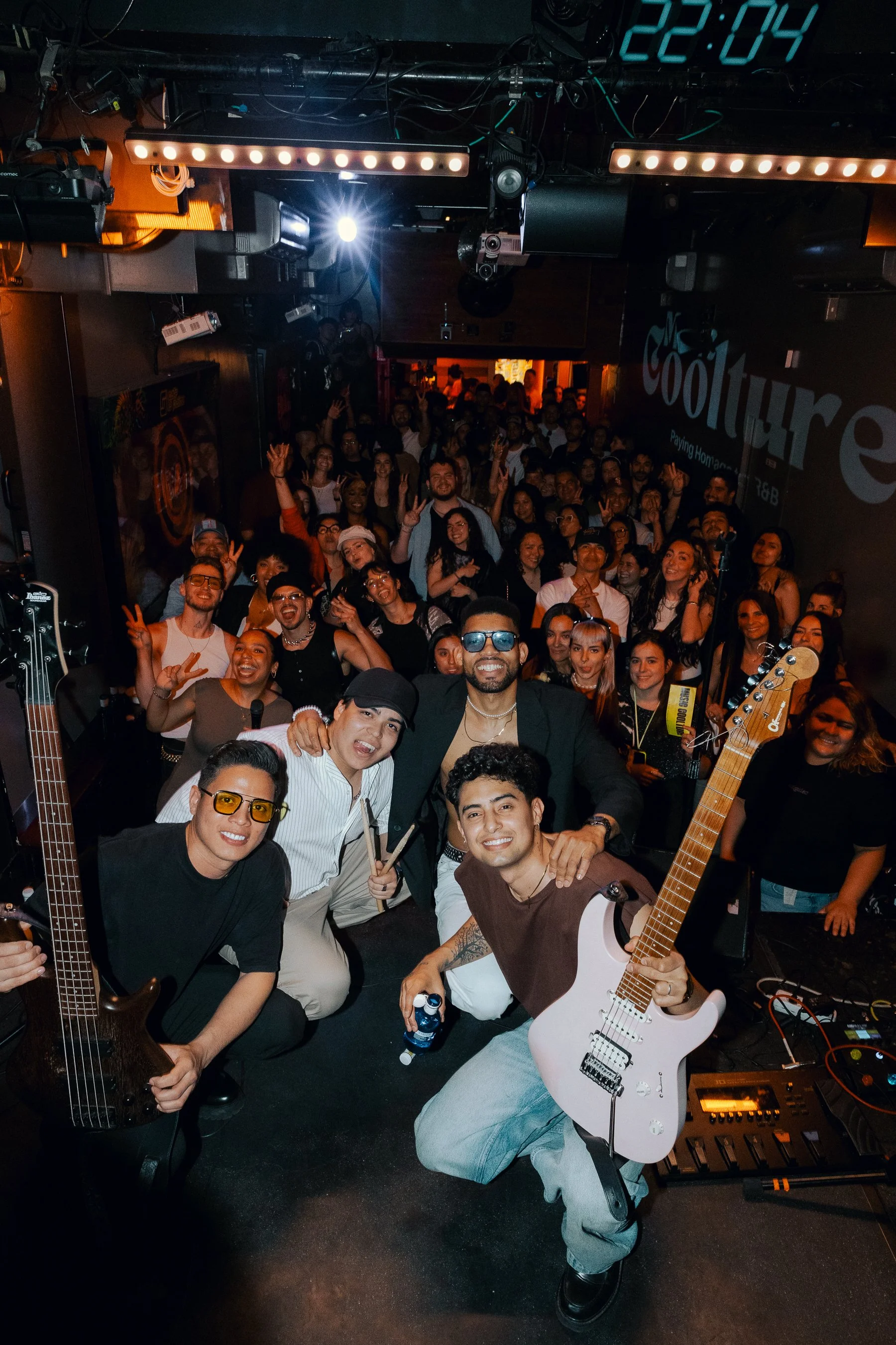 bowie. Un grupo de músicos con instrumentos en un escenario y una multitud en un concierto nocturno.