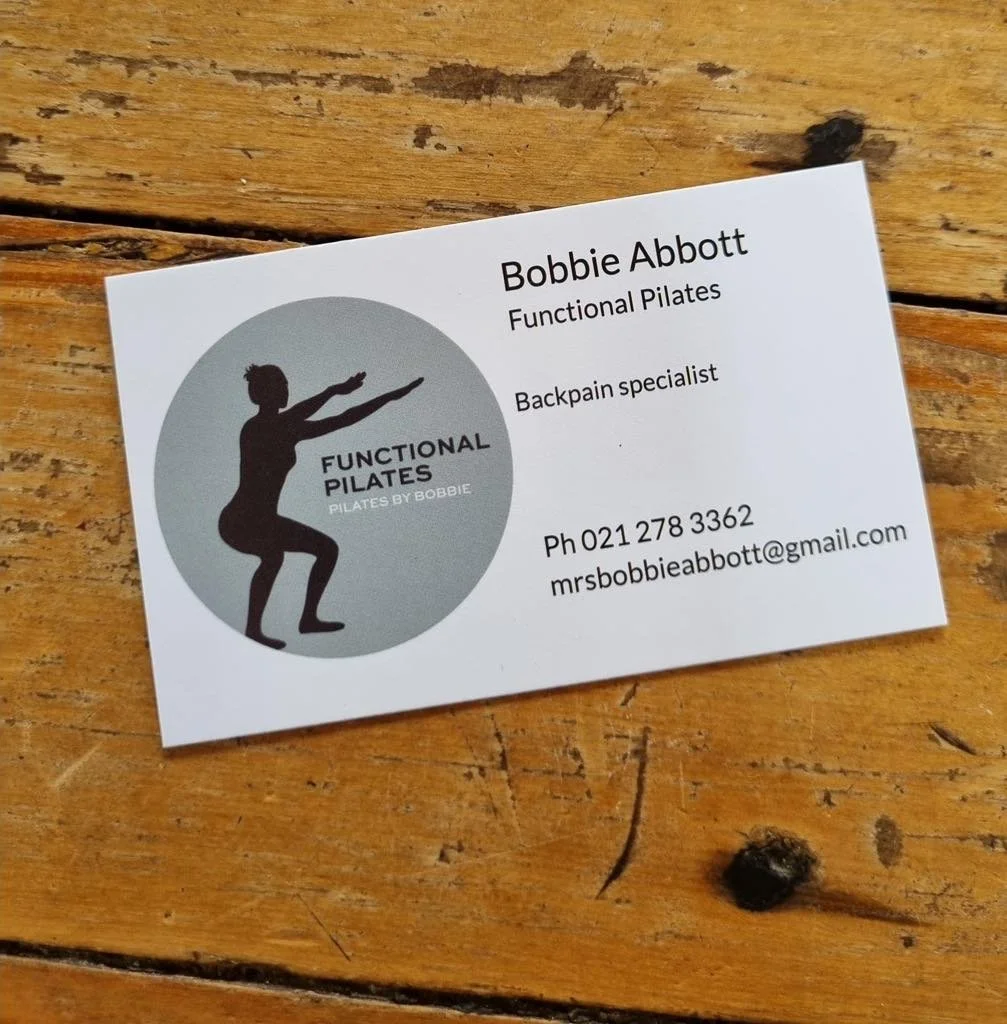 Business card for Bobbie Abbott, a functional Pilates instructor and back pain specialist, featuring a silhouette of a person in a Pilates pose, contact information, and a wooden surface background.