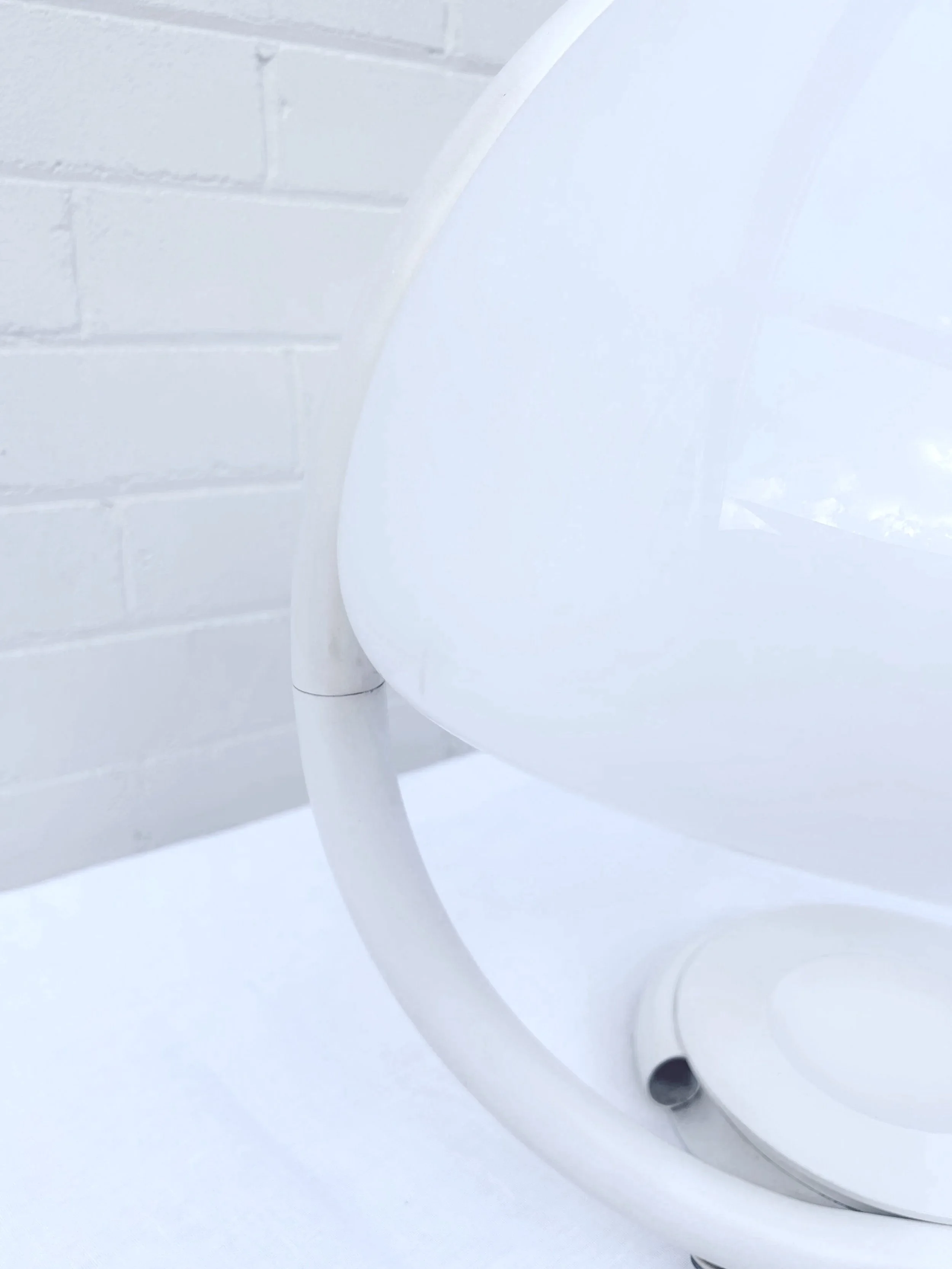 Close-up of a white snake like table lamp with plastic mushroom dome shade