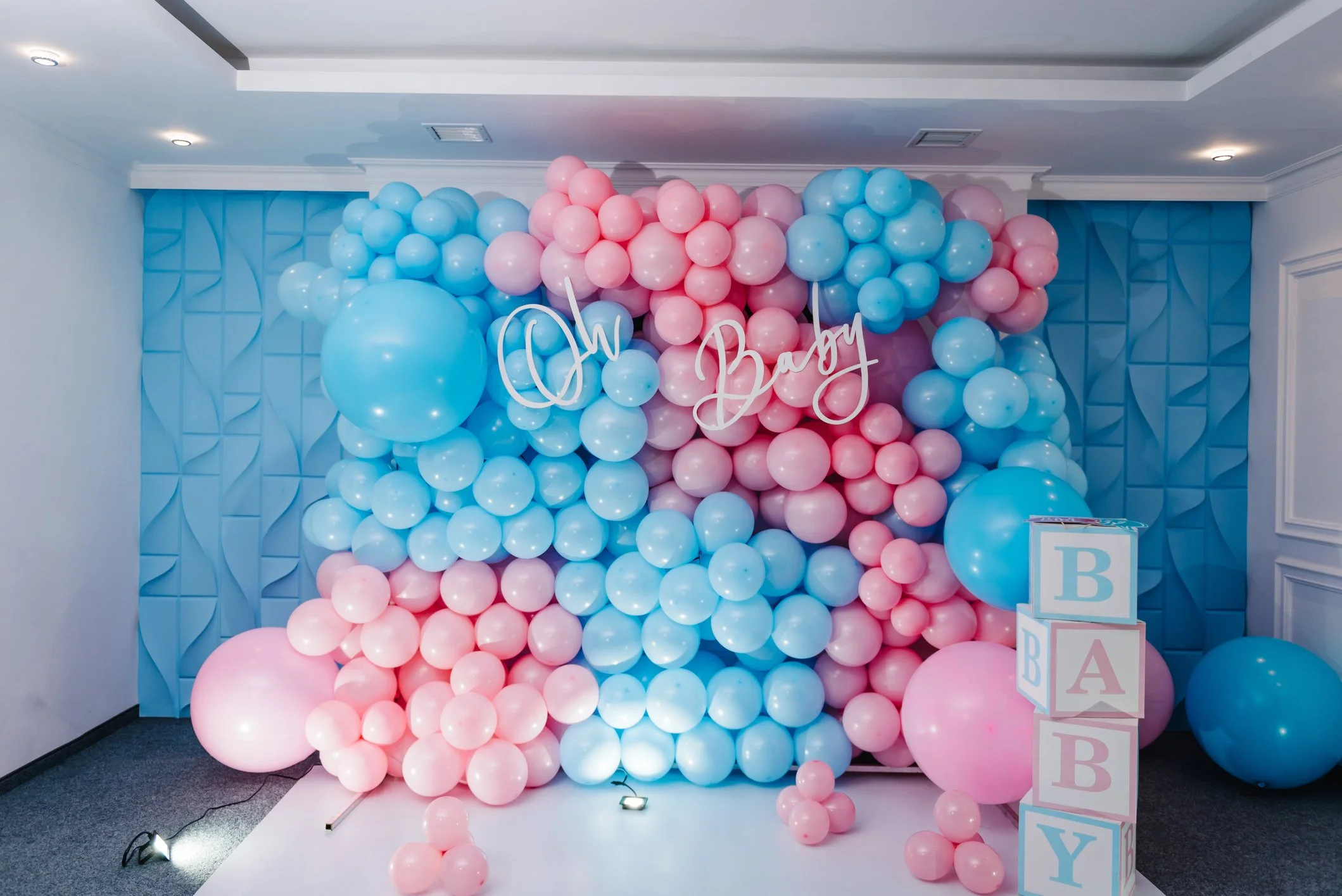 Pink and blue balloon decoration for a baby shower with a sign that says 'Oh Baby' and blocks spelling 'BABY'