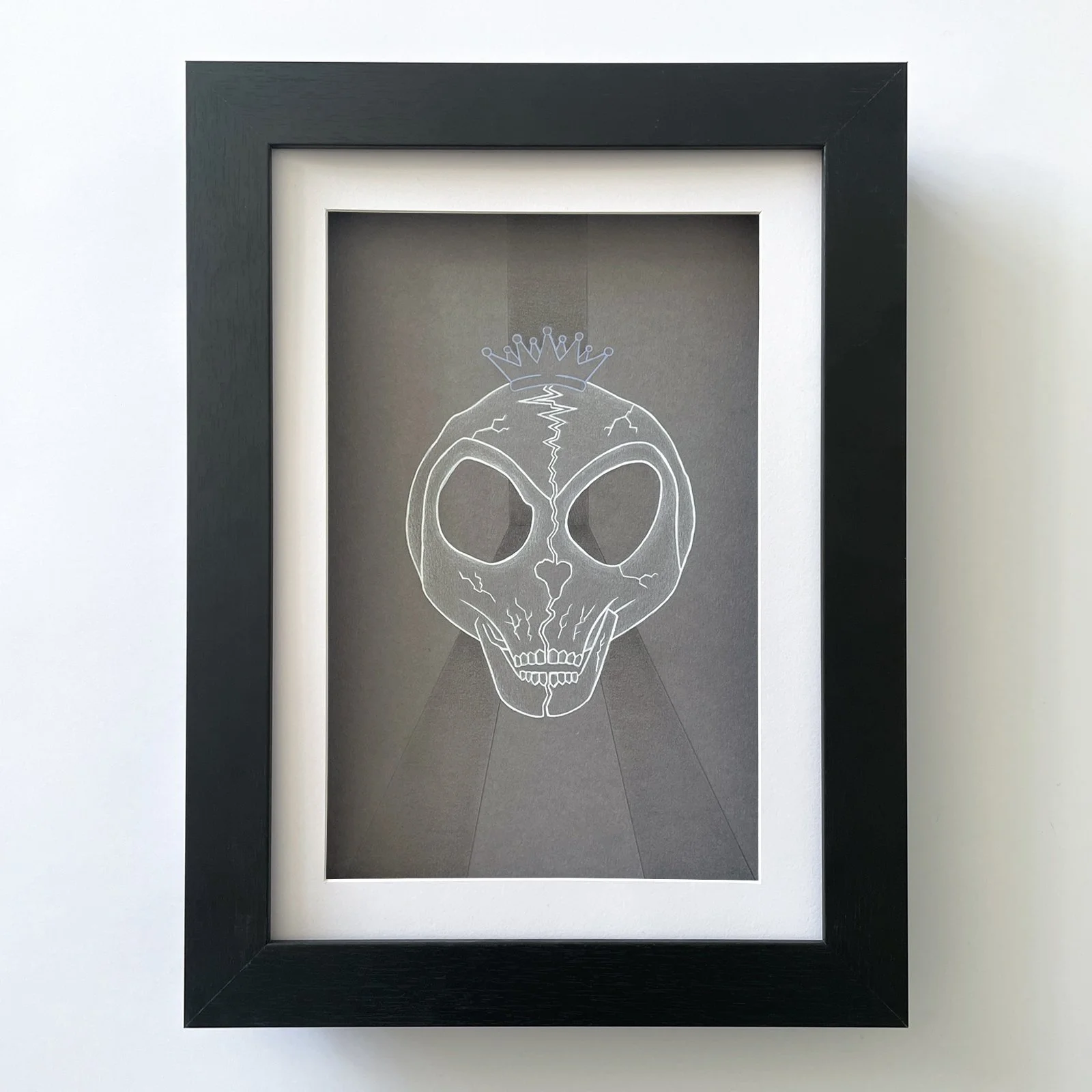 Outkast framed artwork with a mixed media piece (graphite, acrylic paint and gloss varnish) of 2 'ATLien' skull halves meeting. Two seperate paths become one in the eye sockets and the Outkast crown rests on top of the formed skull. 