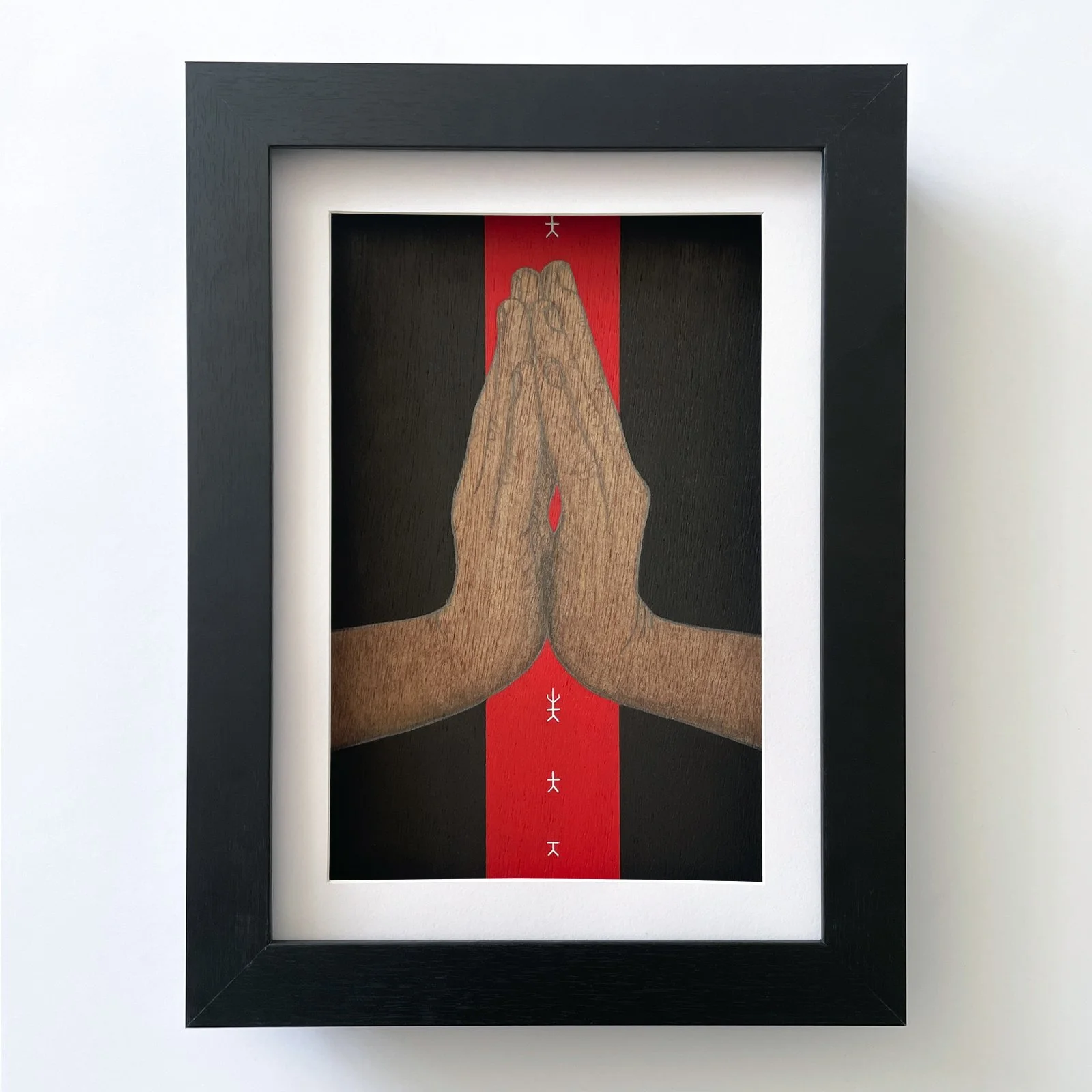 Framed wooden panel with a sketch of hands in Anjali mudra over a striped red acrylic painted path with black background.