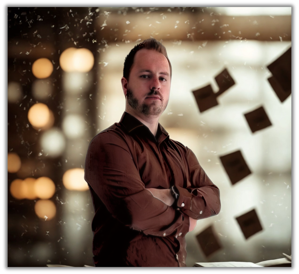 A man with arms crossed standing in front of a glass wall with floating squares mounted on it, with blurred warm lights in the background.