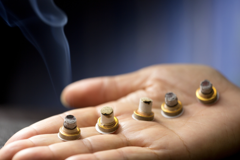 Hand holding lit moxa sticks used in traditional Chinese medicine therapy.