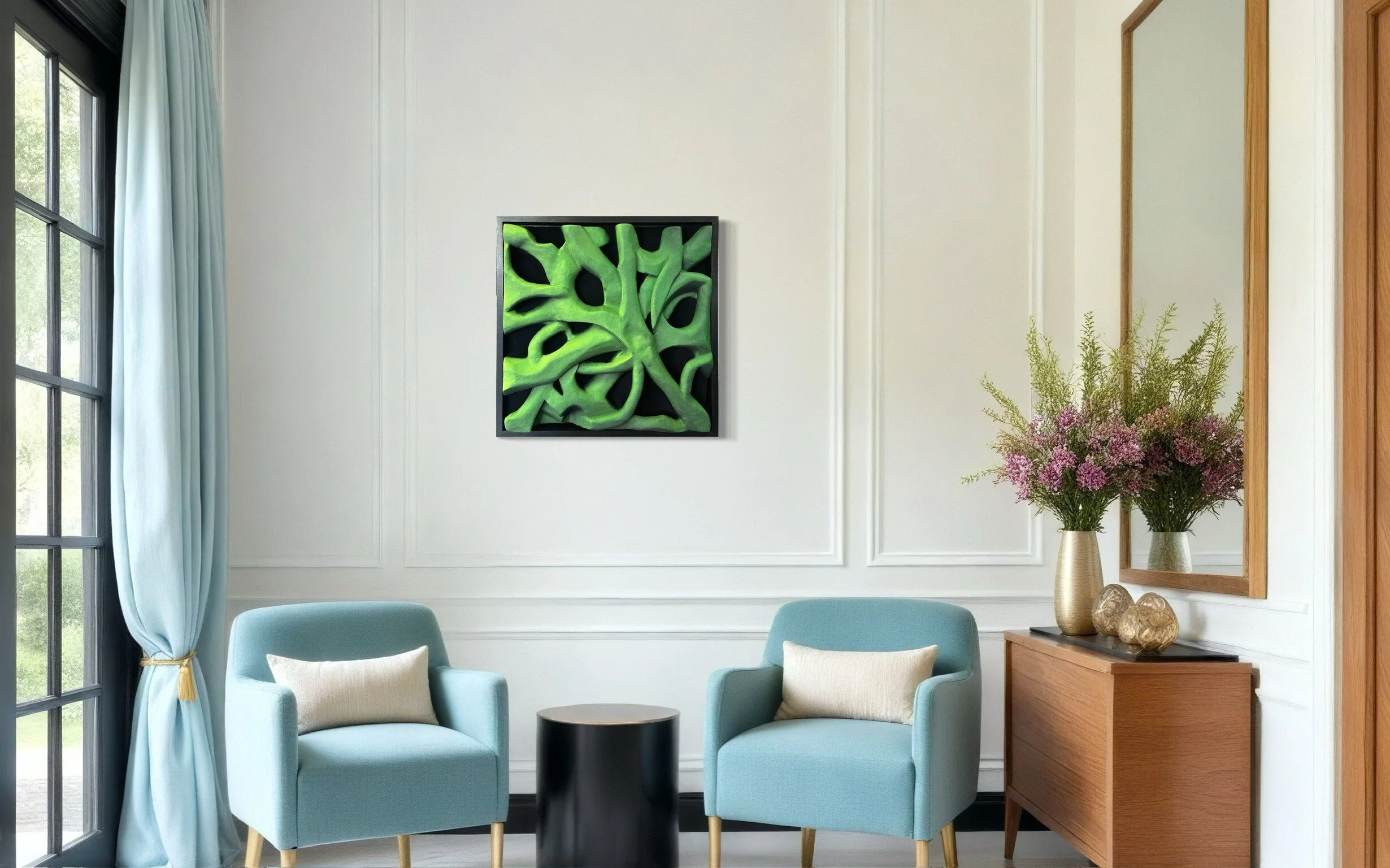 Modern living room with two blue armchairs, a round black table, and a wooden console. There is a framed abstract green artwork on the wall, a large mirror, and a vase with purple flowers and greenery.