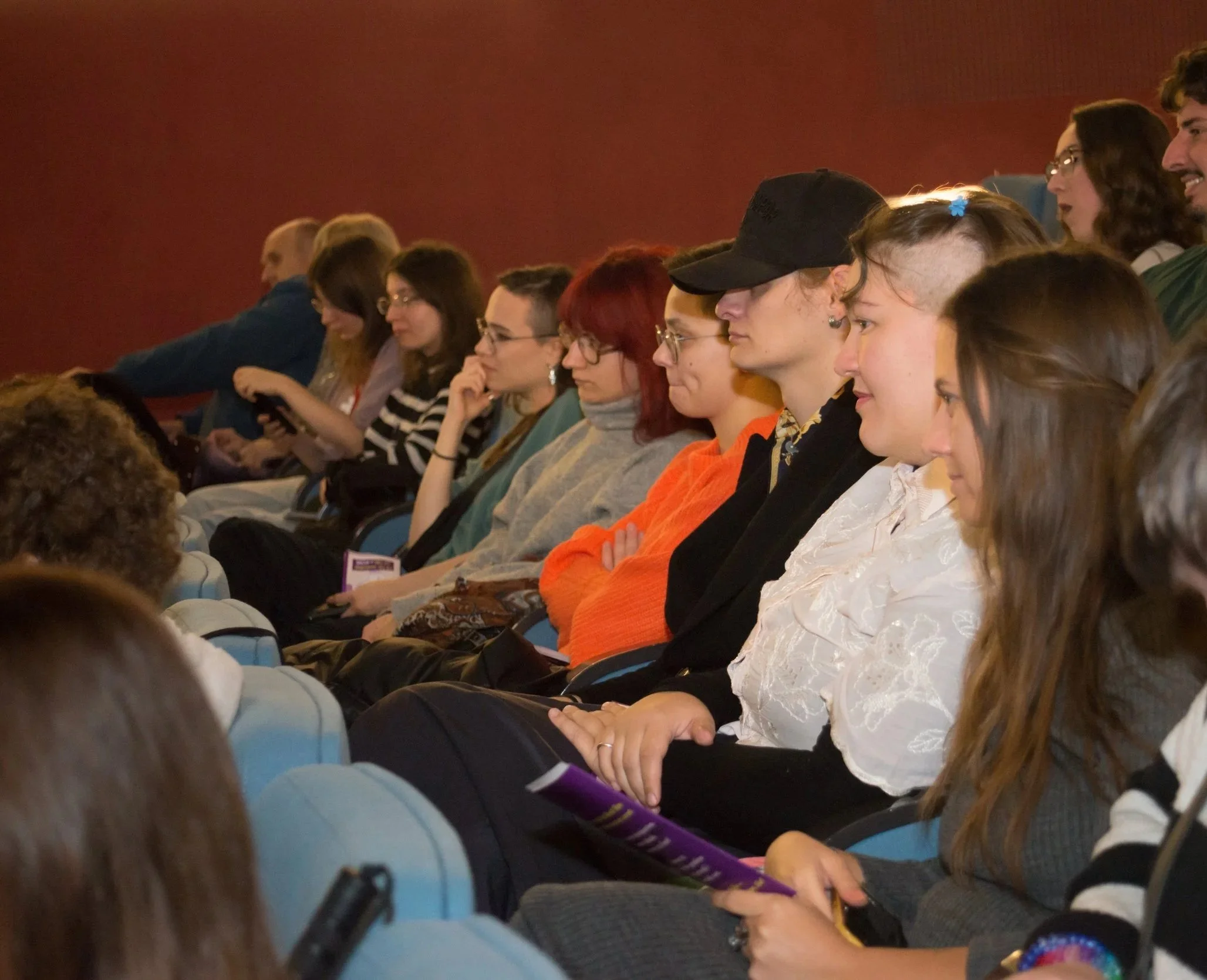  Mlade osobe sede u publici. 