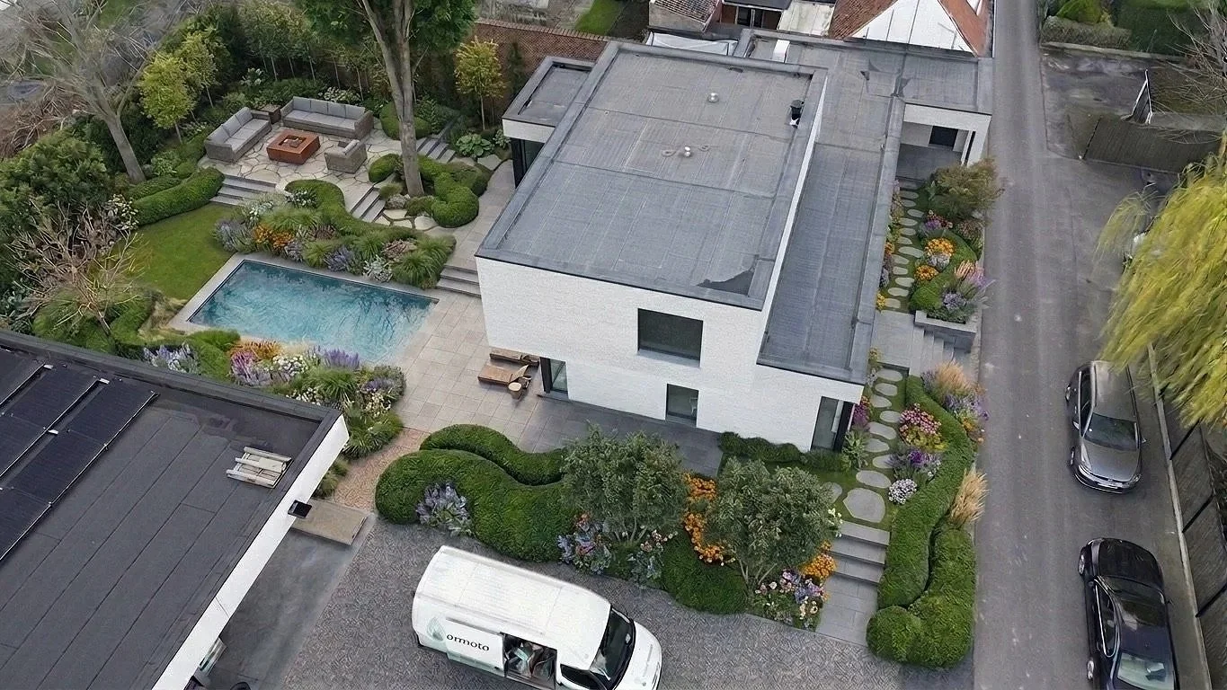 Luchtfoto van modern gebouw met zwembad en verhoogde zitruimte en geparkeerde auto en stapstenen.